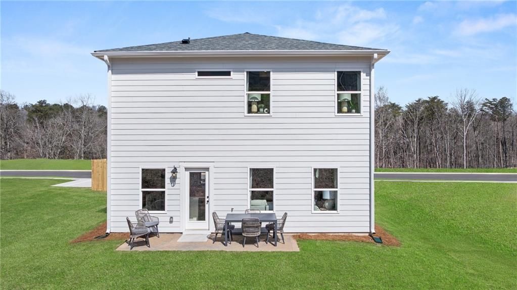 Two-story white craftsman home with covered back patio, outdoor seating, and lush green lawn in The Bluffs, Canton, Georgia