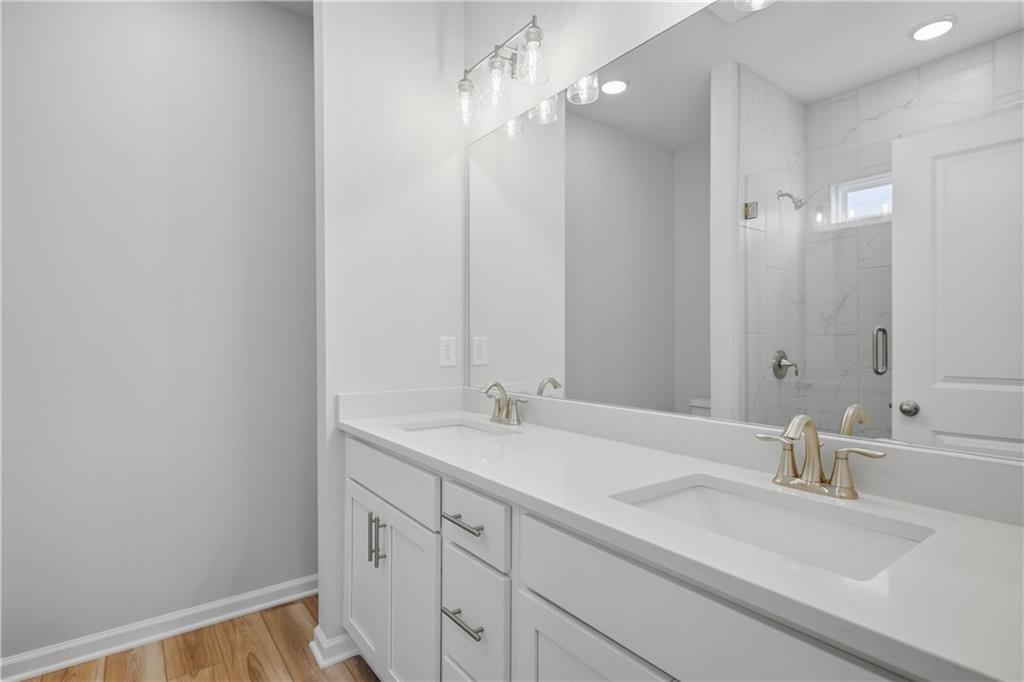 Double vanity bathroom with white cabinetry, marble tile shower, and brushed nickel fixtures in Davidson Homes' The Oconee B, Canton, GA