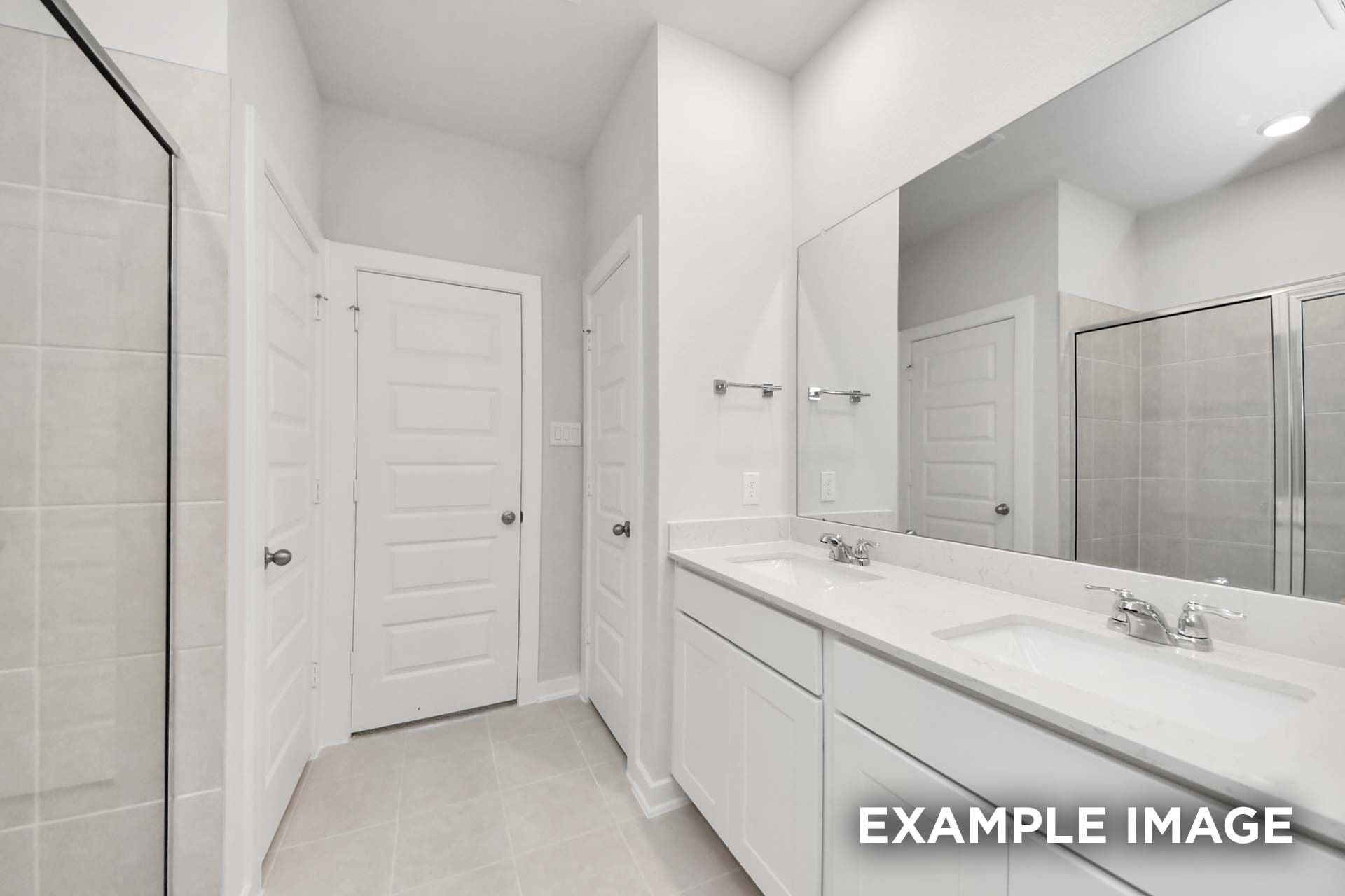 Bright white master bathroom in The Blanco by Davidson Homes featuring double vanity, large mirror, and tiled walk-in shower