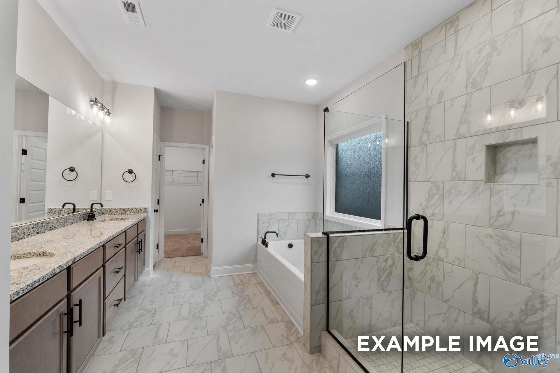 Elegant master bath with freestanding tub, frameless glass shower, double granite vanity in Davidson Homes The Finleigh, Meridianville, Alabama