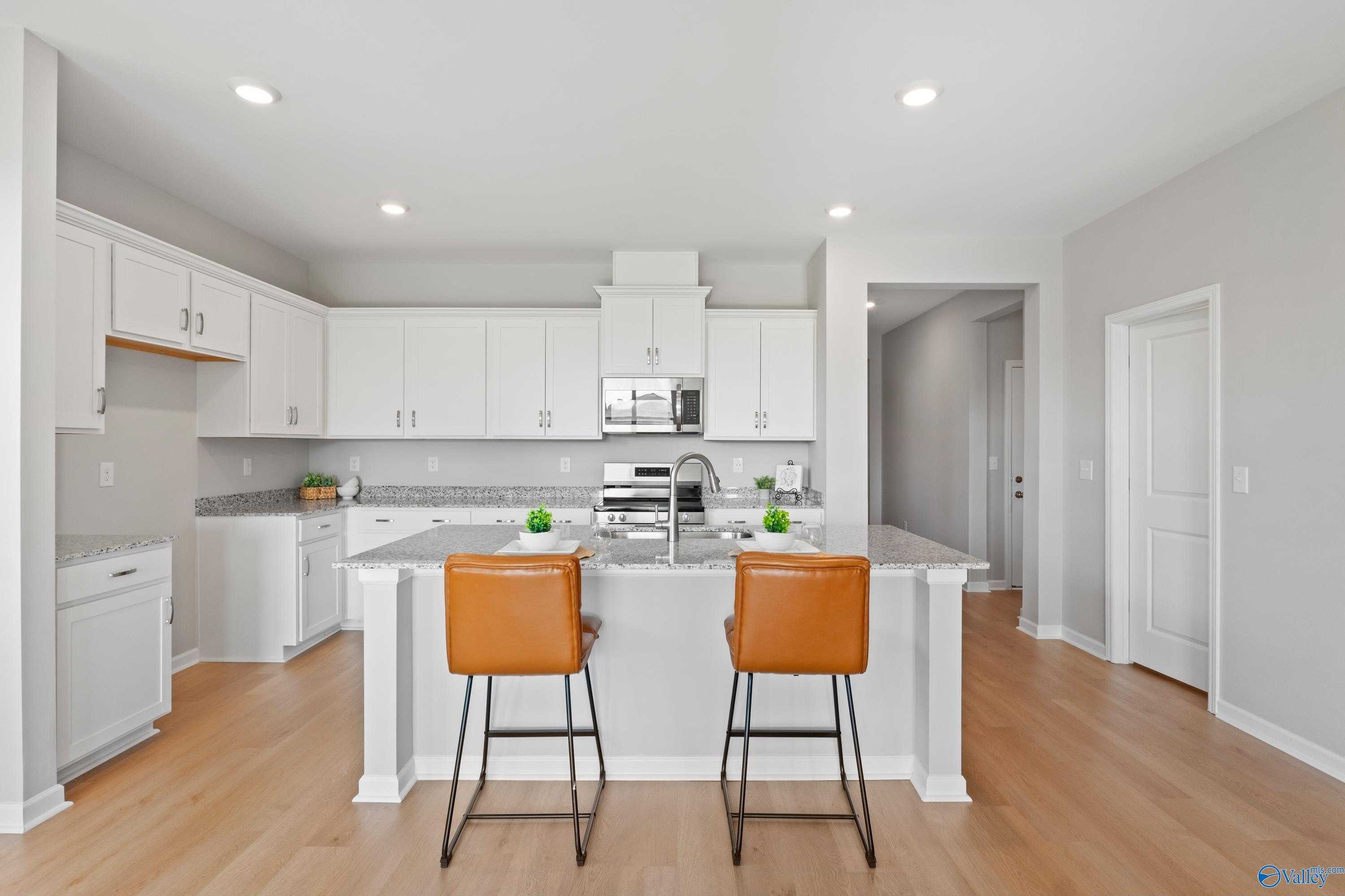 Modern white kitchen with island sink, stainless appliances, orange bar stools in The Aurora 4-bedroom home, Fayetteville, TN