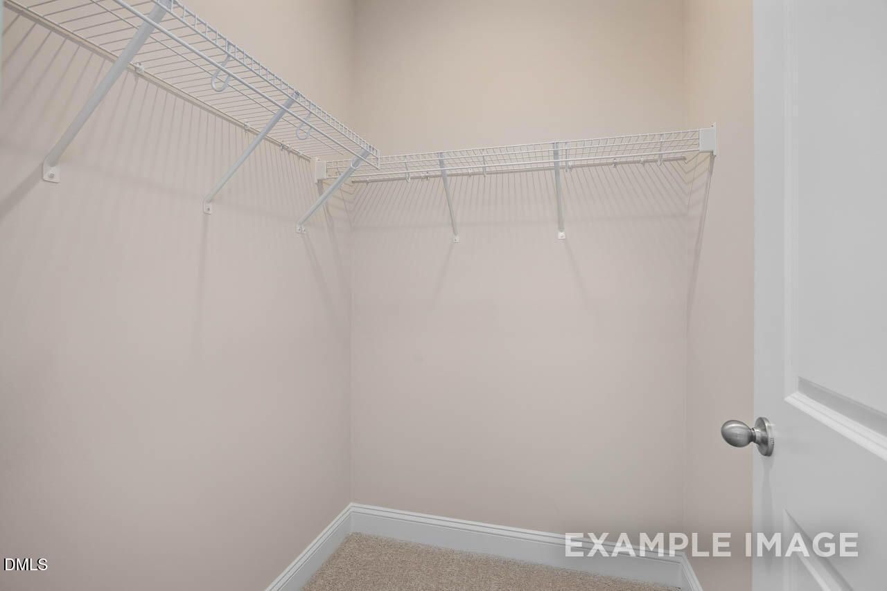 Spacious walk-in closet with white wire shelving and beige walls in The Crawford D master suite, Davidson Homes, Angier, NC