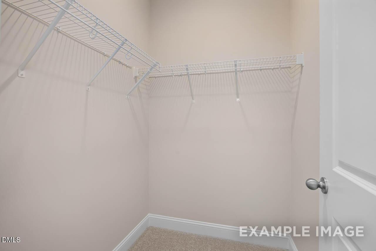 Spacious walk-in closet with white wire shelving and beige walls in The Crawford D master suite, Davidson Homes, Angier, NC