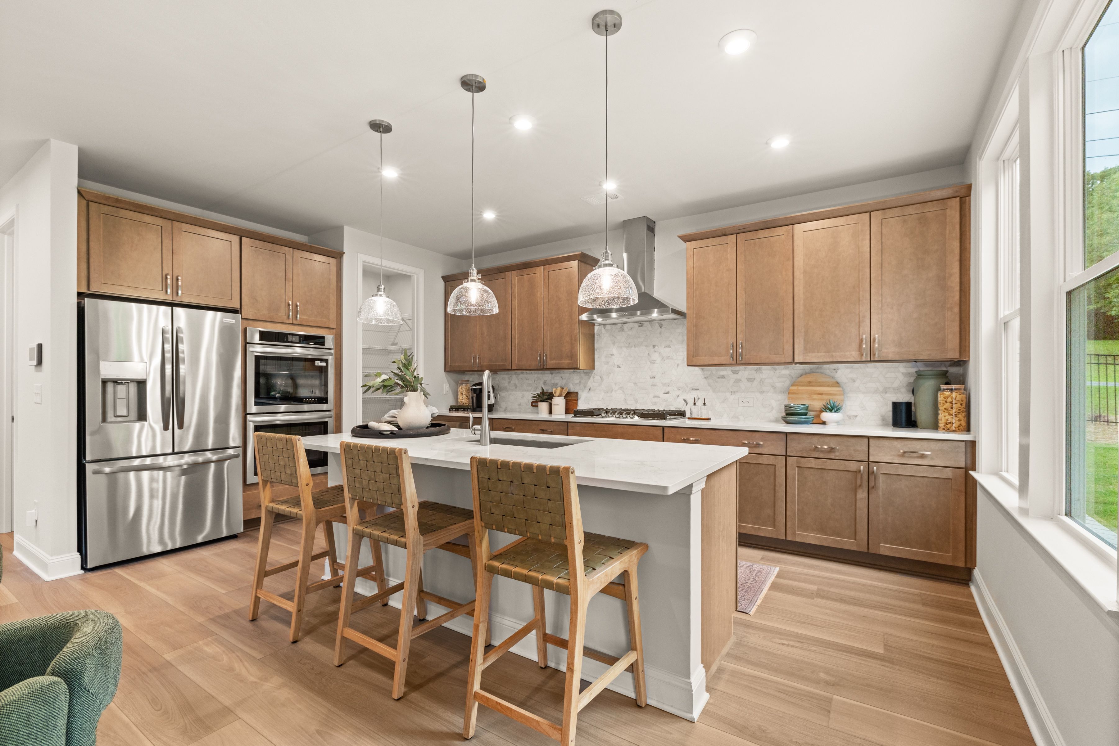 Spacious modern kitchen at Melody Lakeside Estates in Buford GA featuring white cabinets, quartz island, and pendant lights