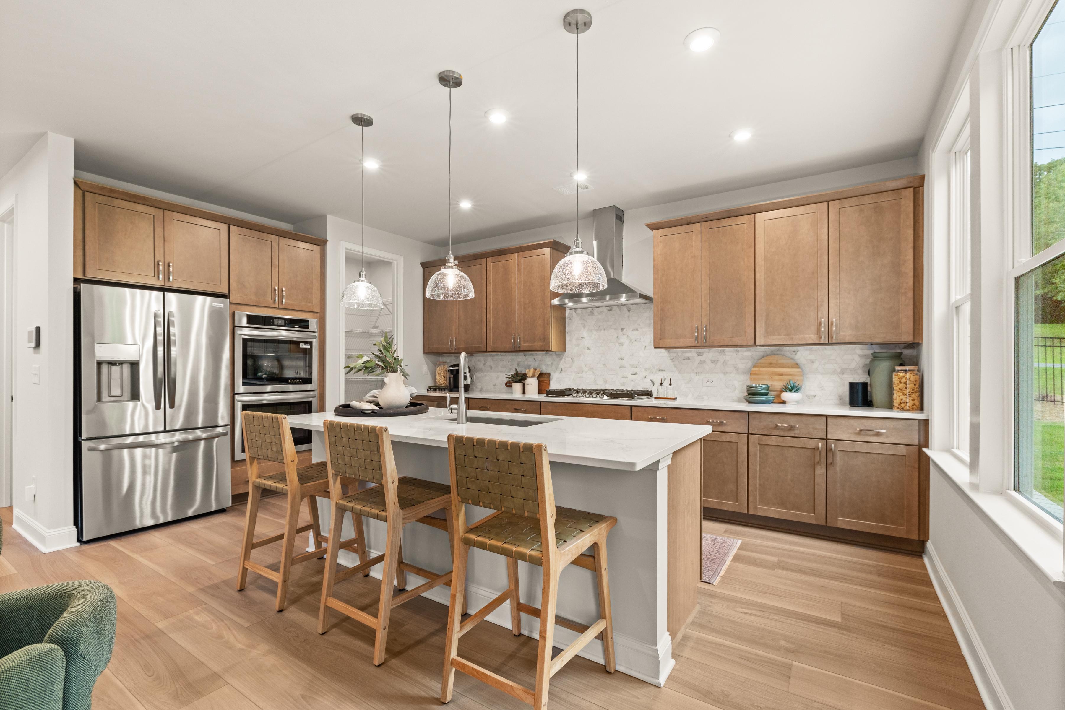 Spacious modern kitchen at Melody Lakeside Estates in Buford GA featuring white cabinets, quartz island, and pendant lights