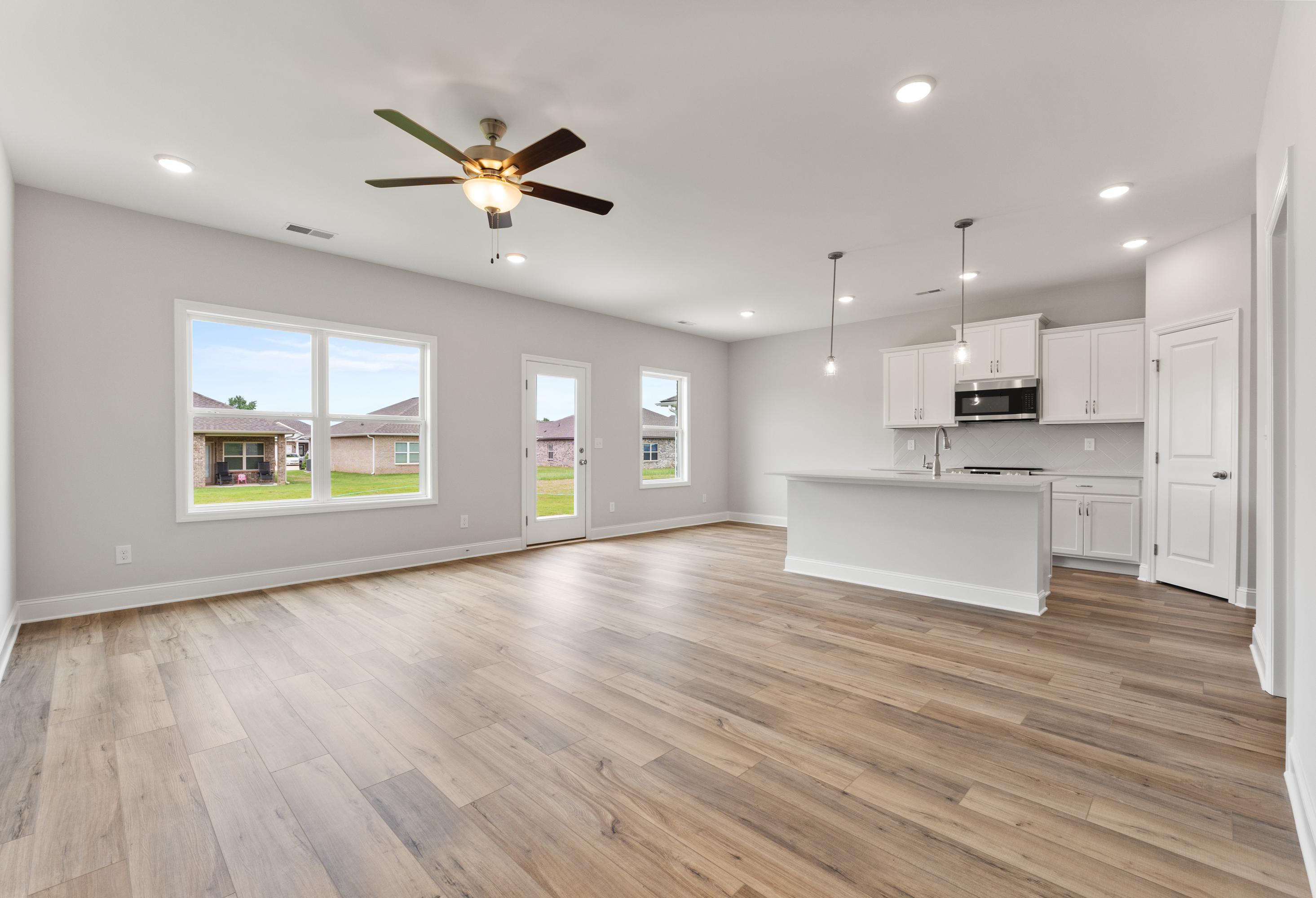 Spacious open-concept kitchen and living area in The Butler Davidson Homes design featuring white shaker cabinets, large island, hardwood floors, and large windows