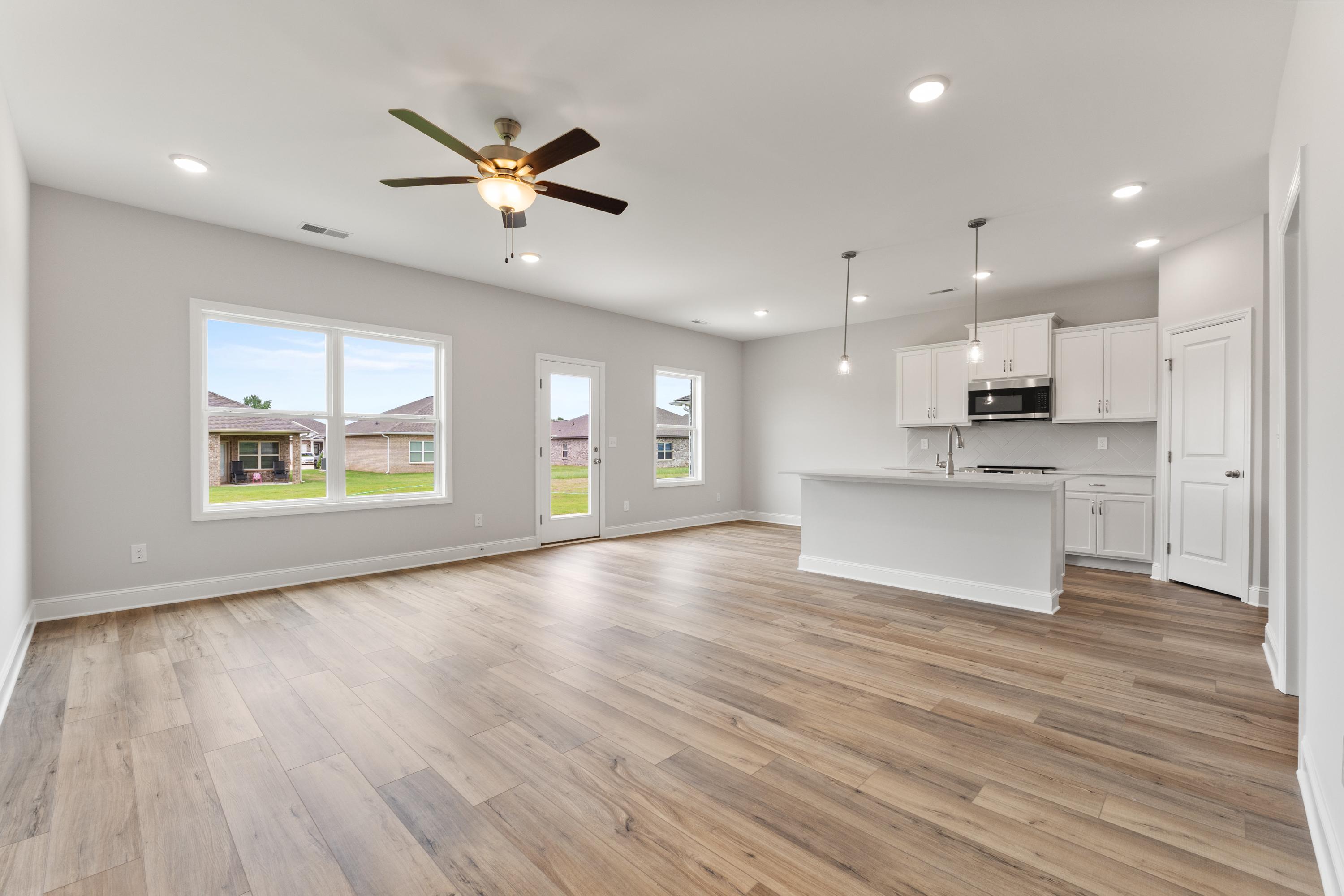 Spacious open-concept kitchen and living area in The Butler Davidson Homes design featuring white shaker cabinets, large island, hardwood floors, and large windows