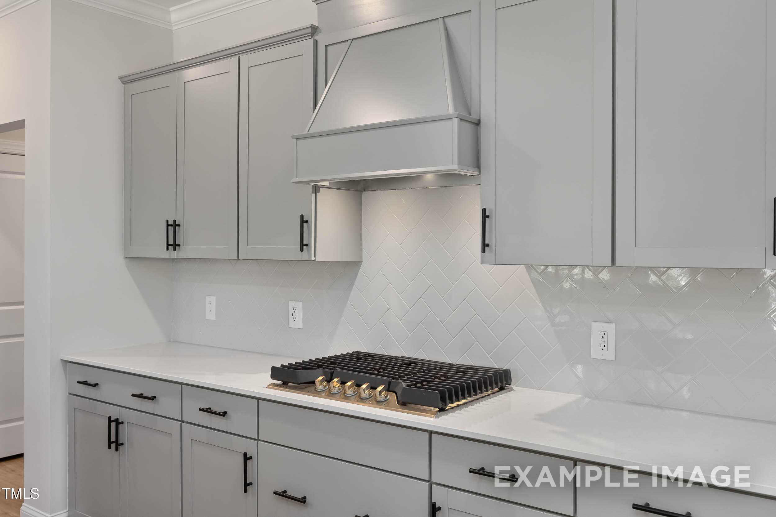 Elegant kitchen with gray shaker cabinets, white quartz counters, herringbone subway backsplash, and stainless gas range in Davidson Homes The Beech B, Raleigh NC