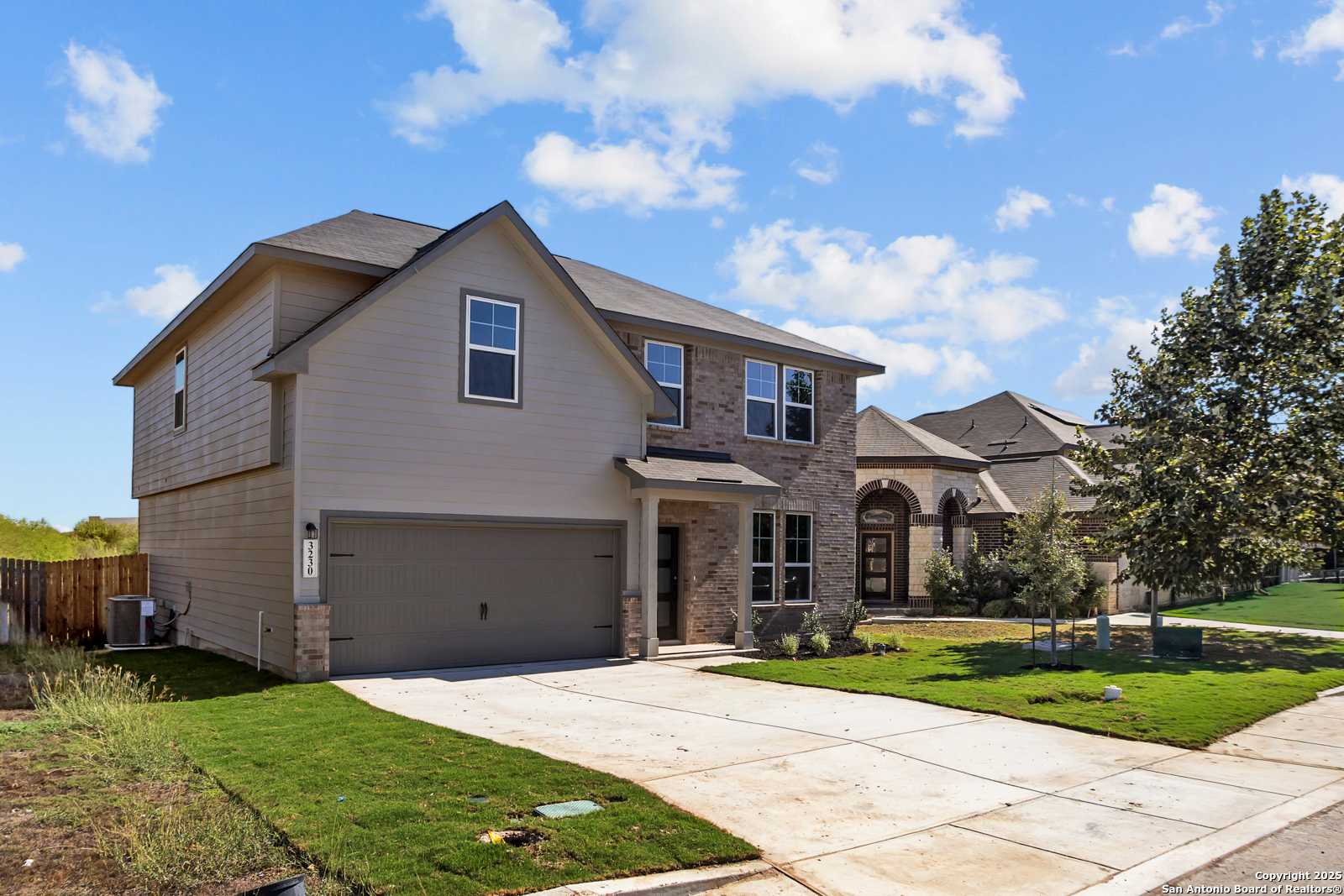 Two-story beige home with brick accents, 2-car garage, and landscaped yard in Horizon Pointe, Converse, Texas - Davidson Homes Murray F