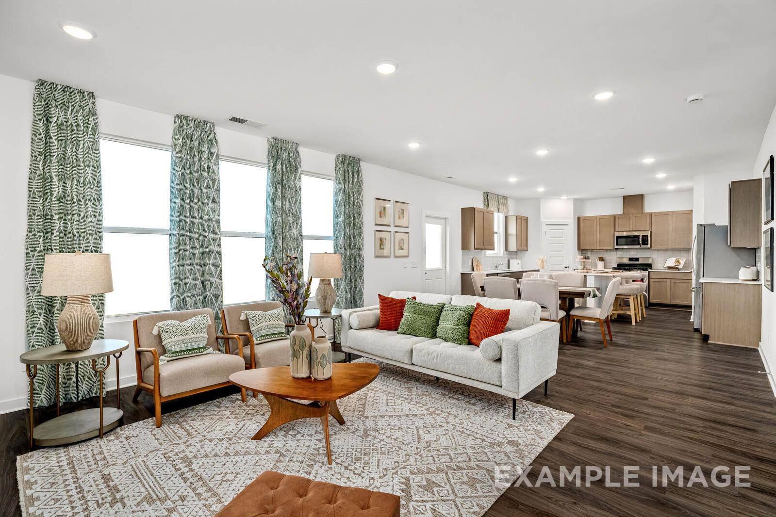 Spacious open-concept living room in The Gordon C home with white sofa, patterned rug, and adjacent kitchen island