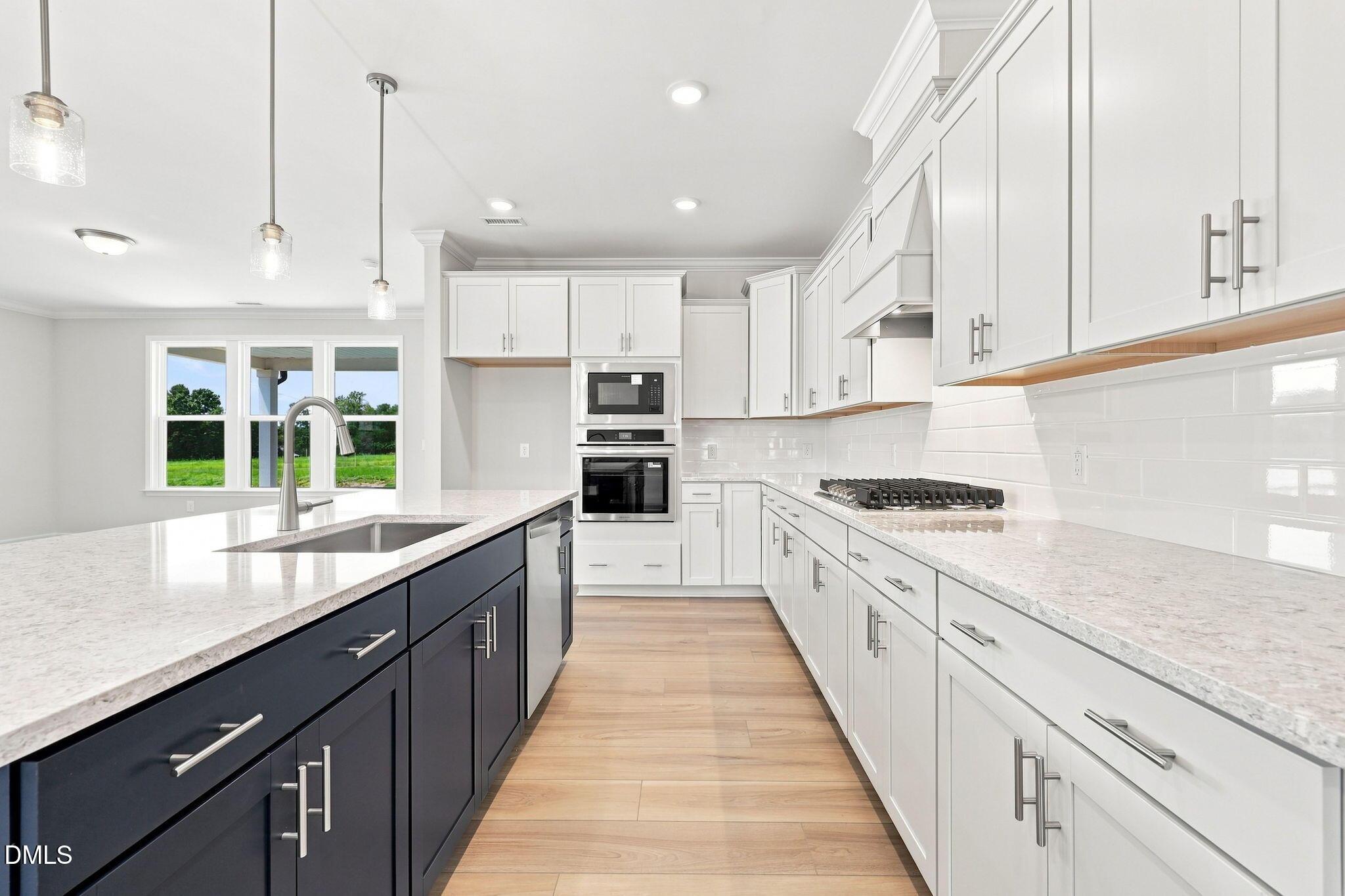 Modern kitchen with white cabinets, dark blue island, and quartz countertops in The Magnolia B at Retreat at North Main.