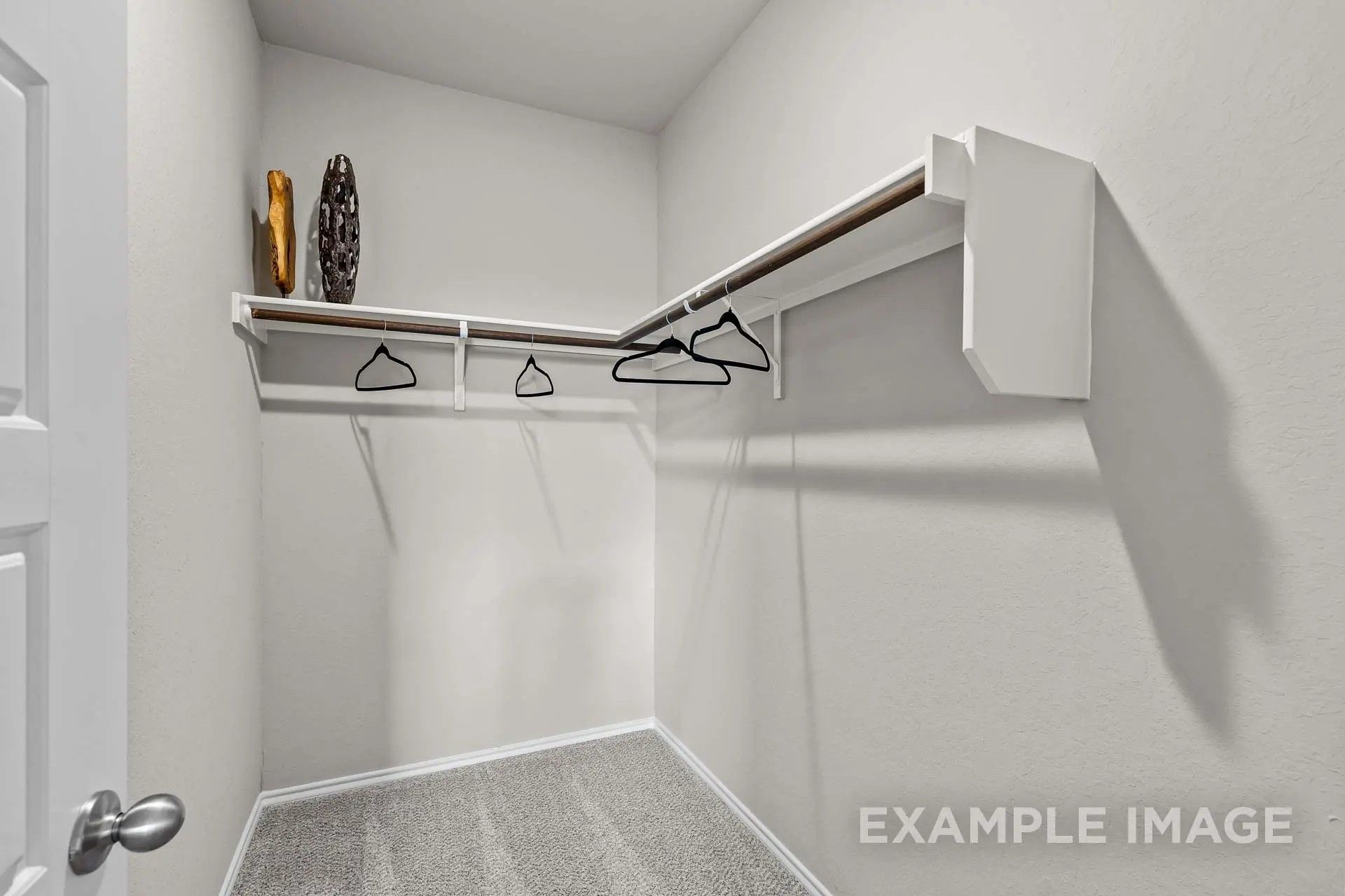 Walk-in closet with white shelving and hanging rods in The Sabine H floor plan by Davidson Homes in Heartland, Texas.