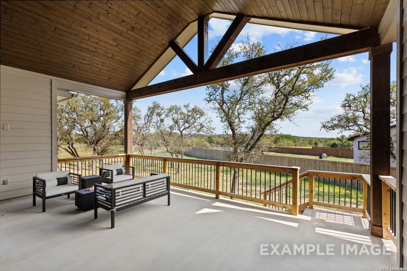 Covered patio with vaulted wood ceiling and outdoor seating at The Garner C home in The Reserve at Potranco Oaks, TX.