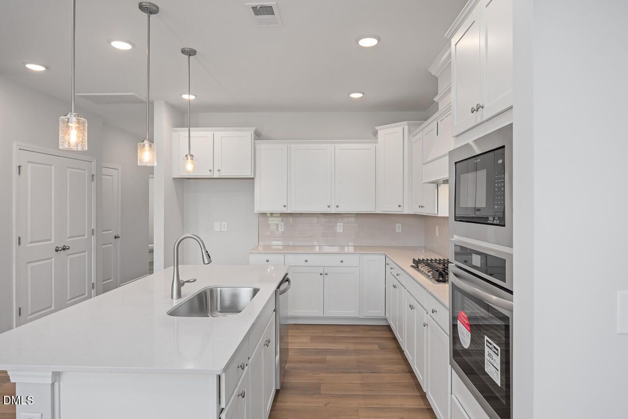Modern kitchen with white cabinets, quartz island, and stainless appliances in The Graham floor plan, Springvale, NC.