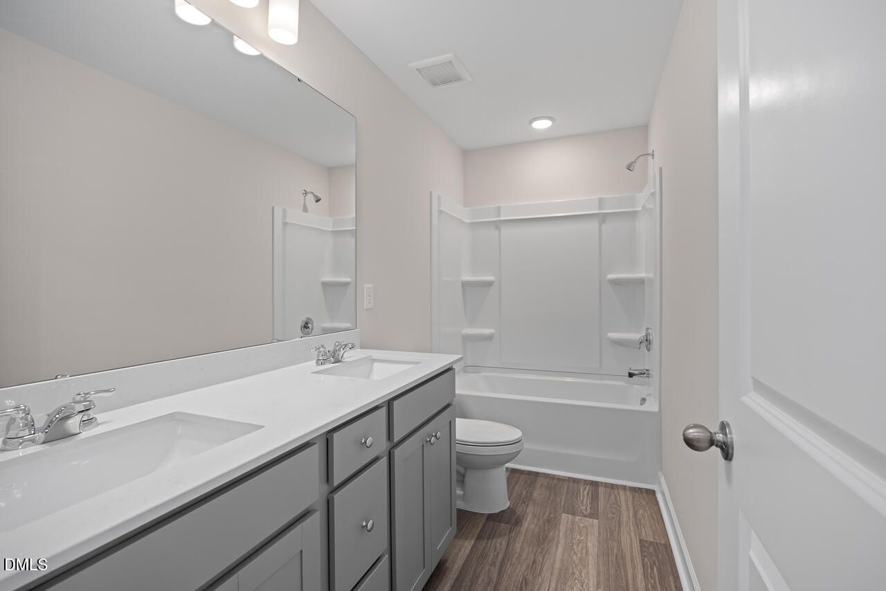 Modern bathroom with dual-sink grey vanity and tub-shower combo in The Graham floor plan at Springvale, Fuquay-Varina, NC.