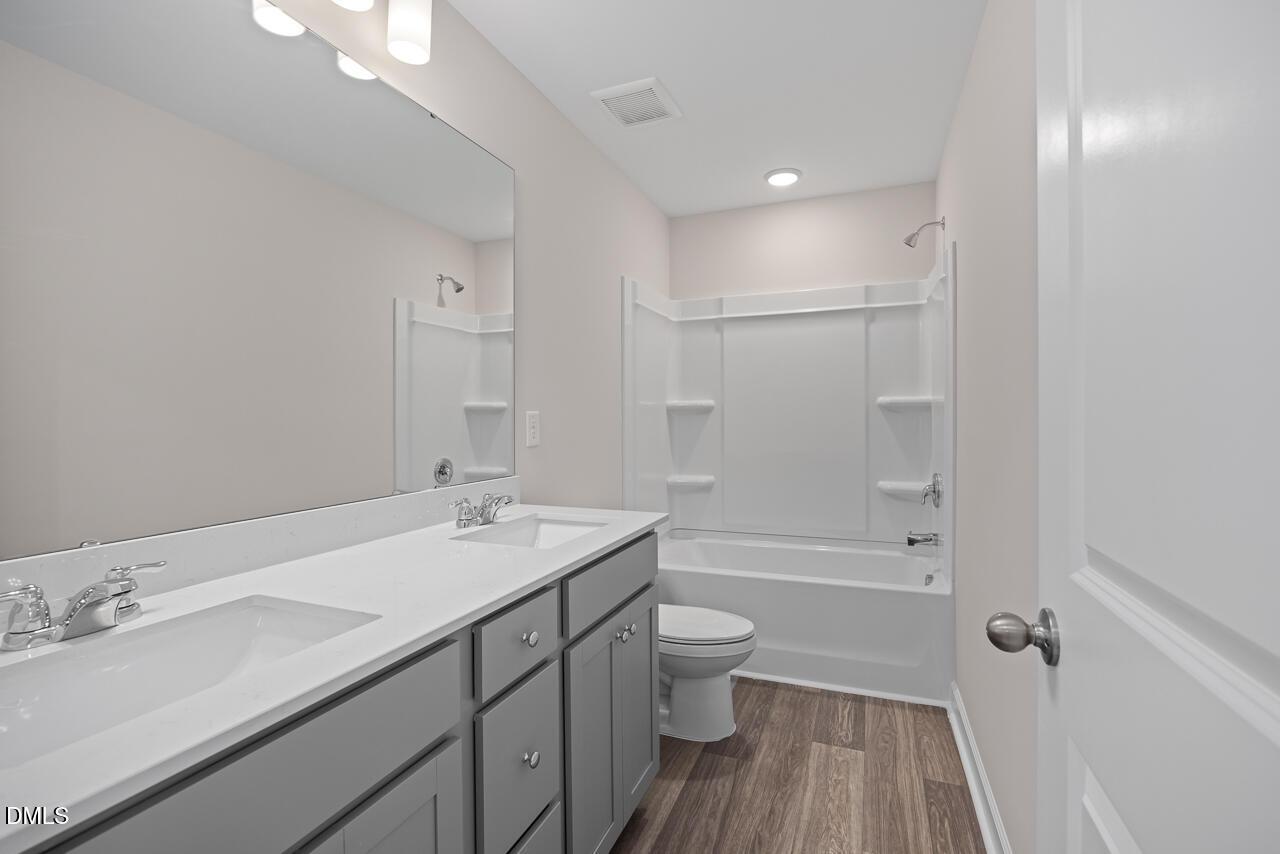 Modern bathroom with dual-sink grey vanity and tub-shower combo in The Graham floor plan at Springvale, Fuquay-Varina, NC.