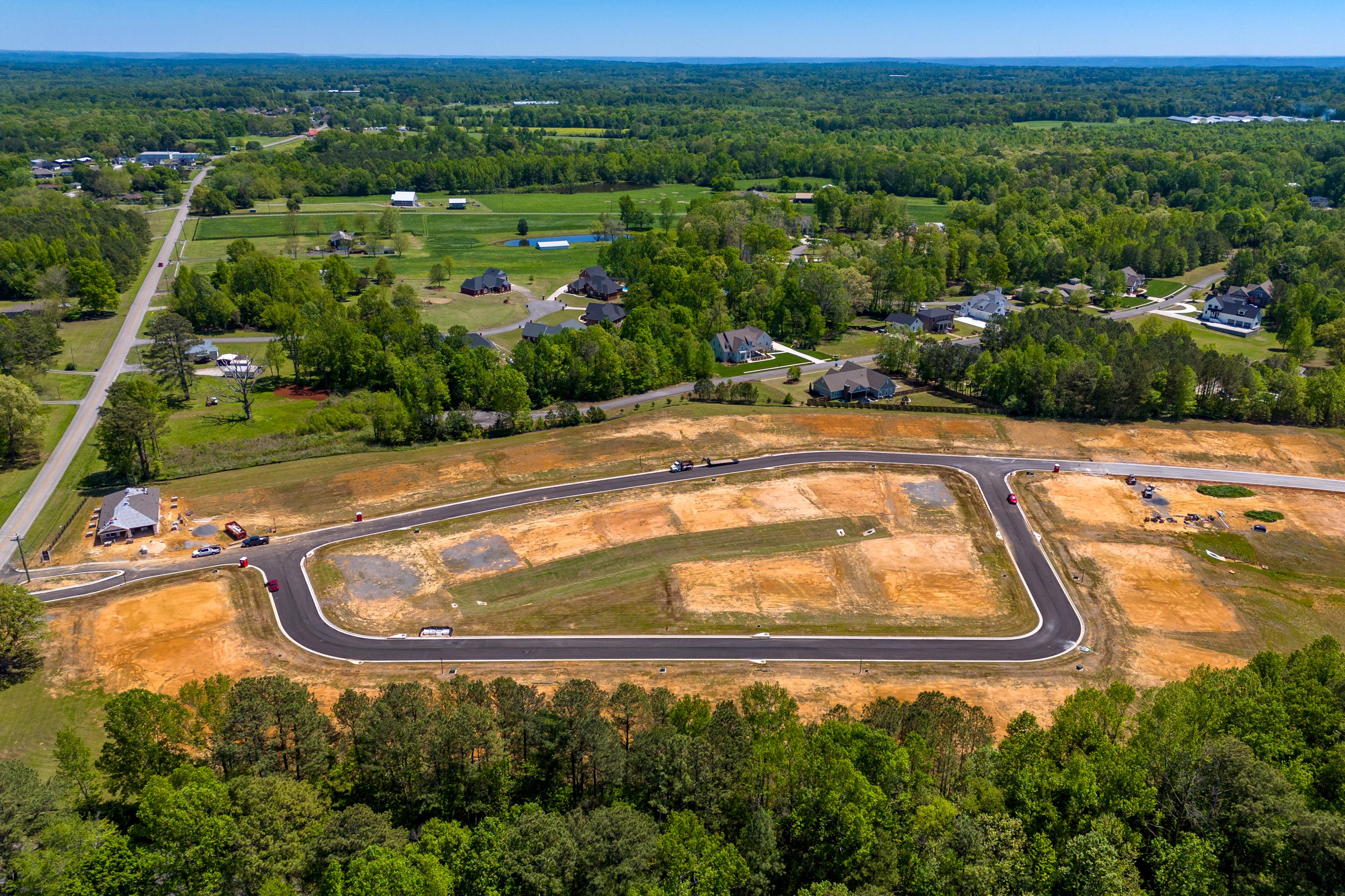 Aerial view of The Highlands construction site in Arab Alabama featuring cleared home lots new roads and surrounding forests