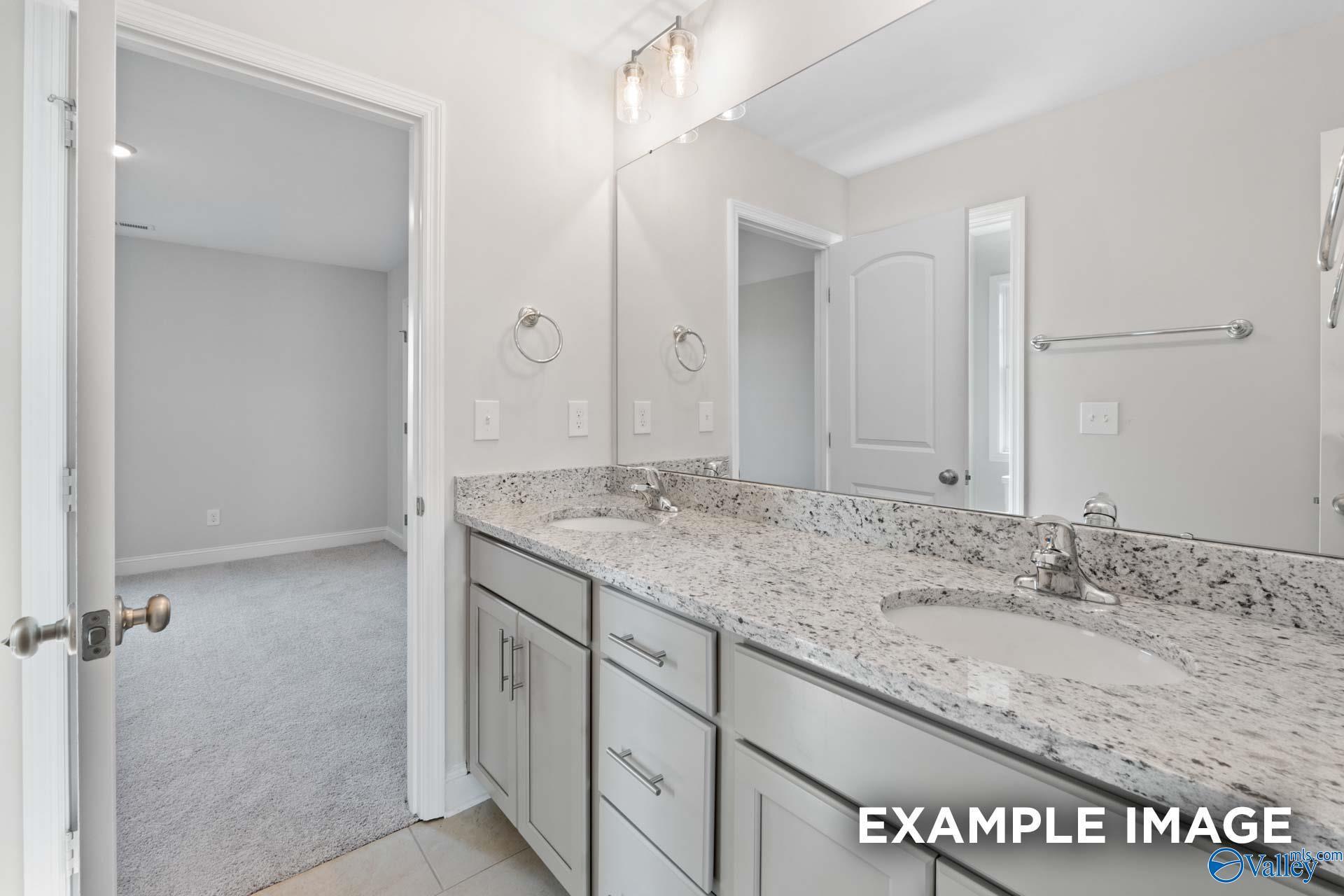 Elegant double vanity with granite countertops, large mirror, and modern fixtures in Davidson Homes Madison A bathroom, Toney, Alabama