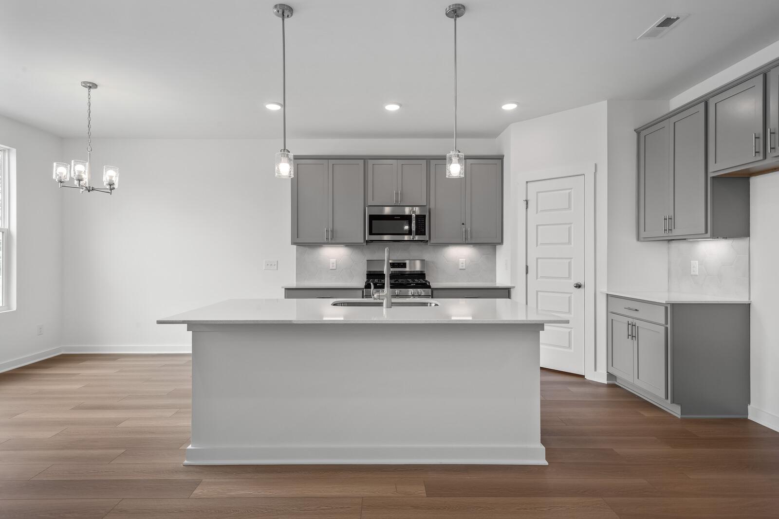 Spacious kitchen in The Asheville featuring white quartz island, stainless steel appliances, gray cabinets, and pendant lights