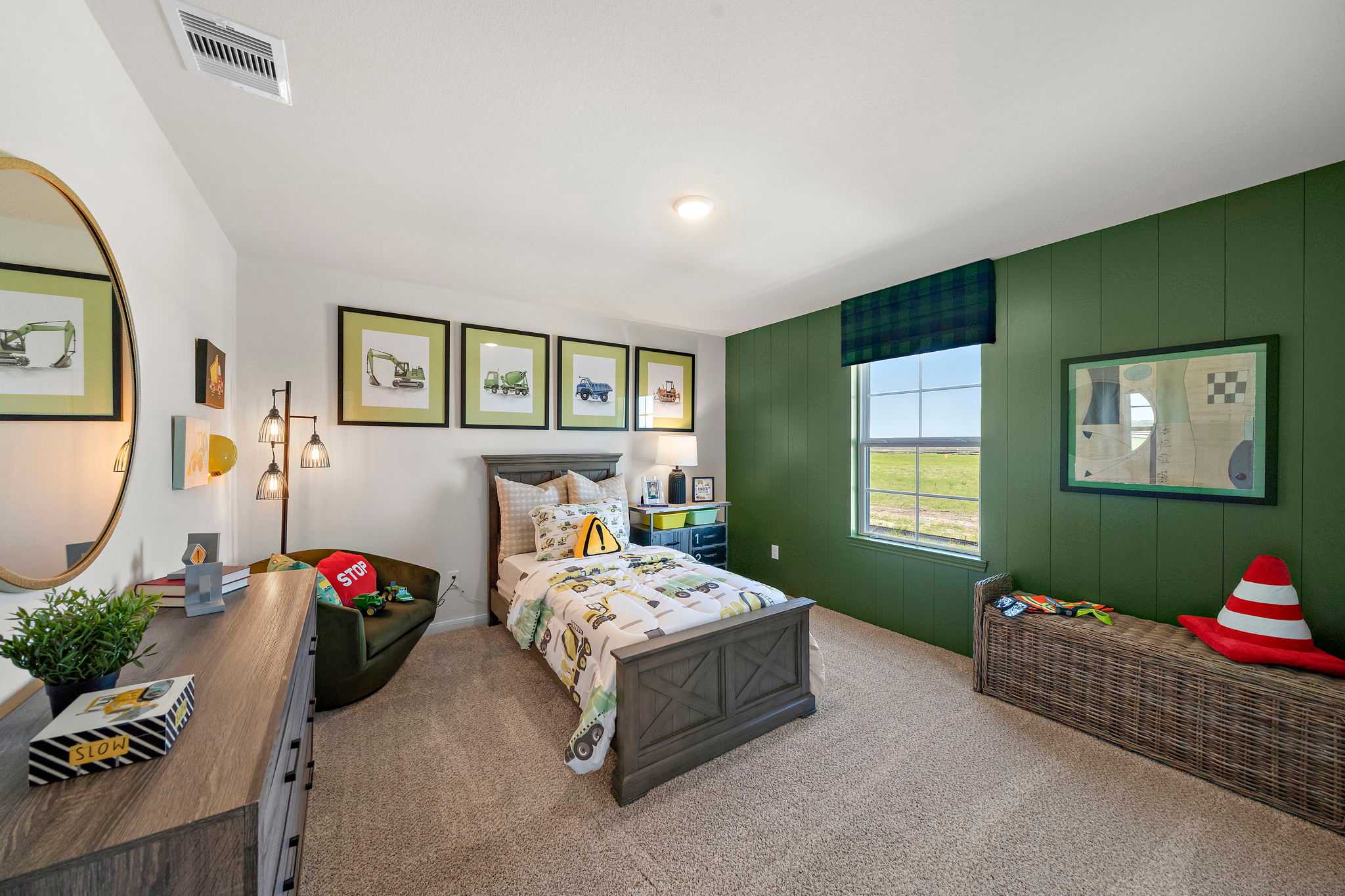 Boy's bedroom featuring green accent wall, twin bed with tractor bedding, and toy car posters at River Ranch Meadows in Dayton, Texas