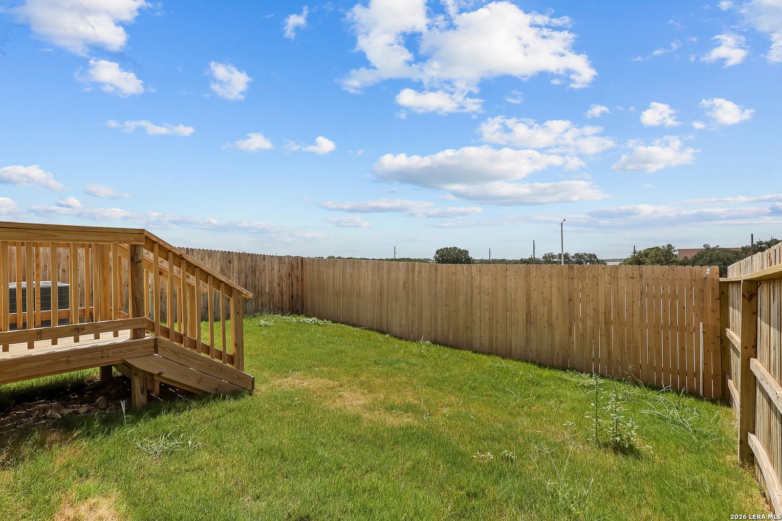 Private fenced-in backyard with a wooden deck at The Gillian B floor plan in Meadows at Oak Creek, San Antonio, Texas.