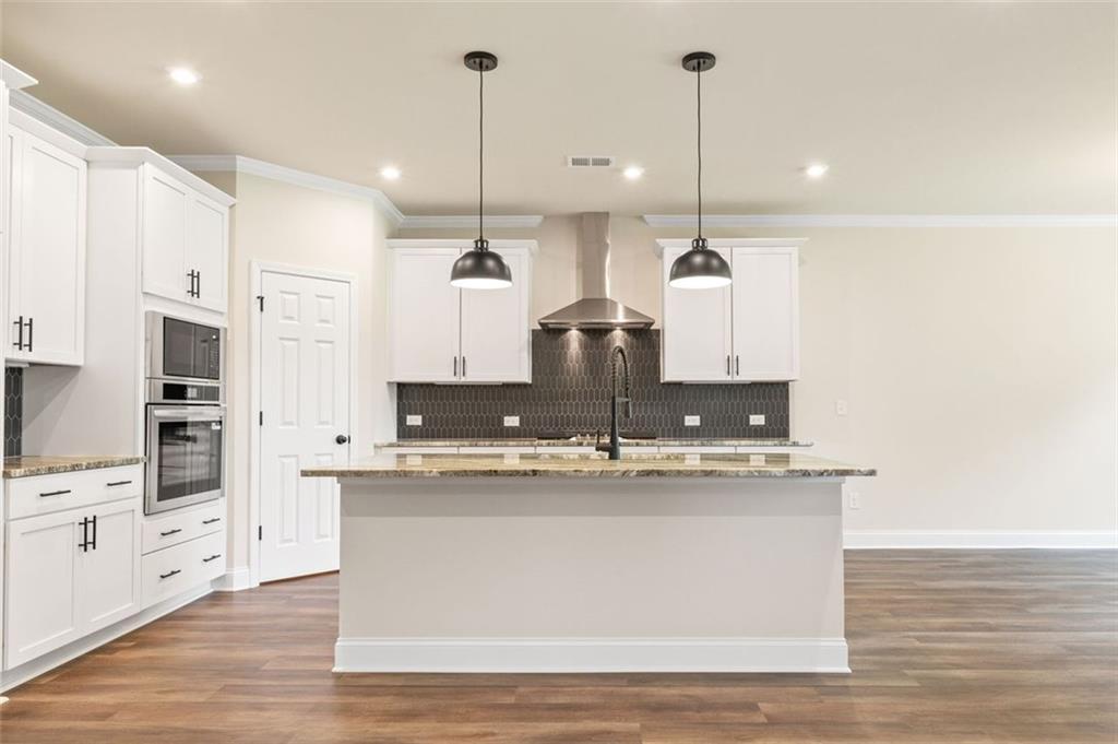 Modern white kitchen with granite island, stainless appliances, subway tile backsplash in Davidson Homes The Harrison G, Hoschton, GA