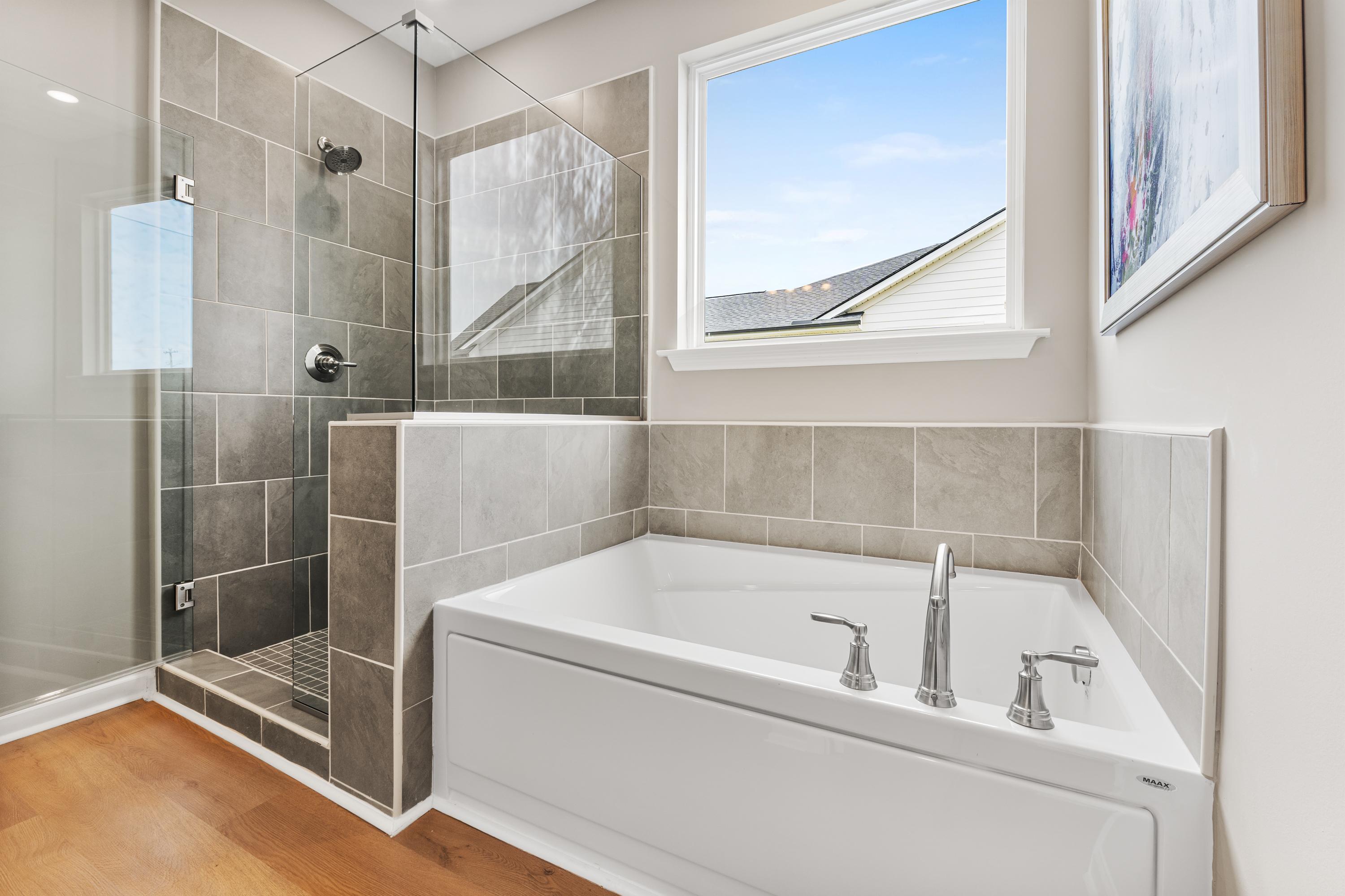 Luxury master bathroom at The Meadows at Hampton Cove in Owens Cross Roads AL with gray tile glass shower and freestanding soaking tub