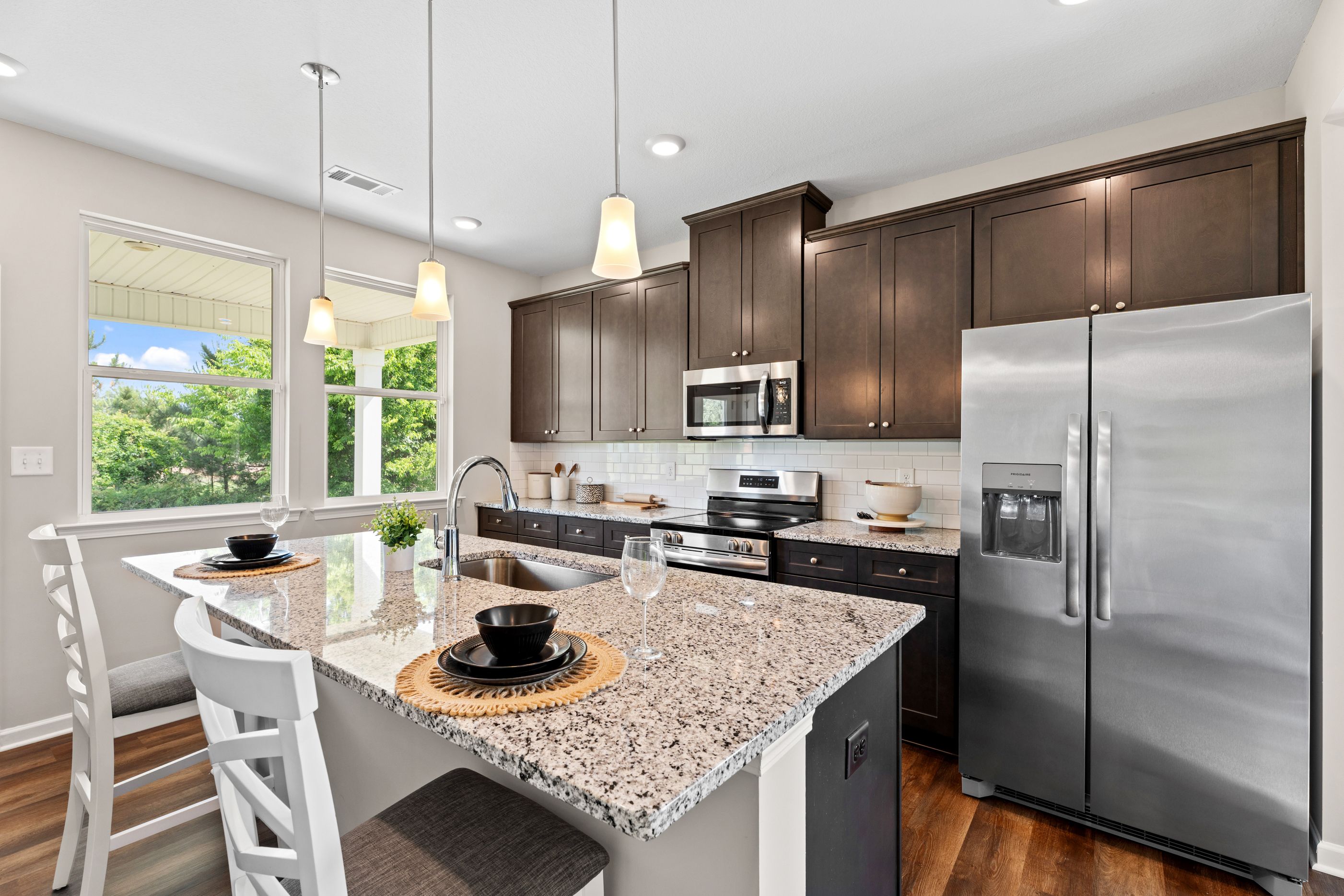 Modern kitchen at Ivy Glen in Perry, GA by Davidson Homes featuring granite island, dark cabinetry, and stainless appliances.
