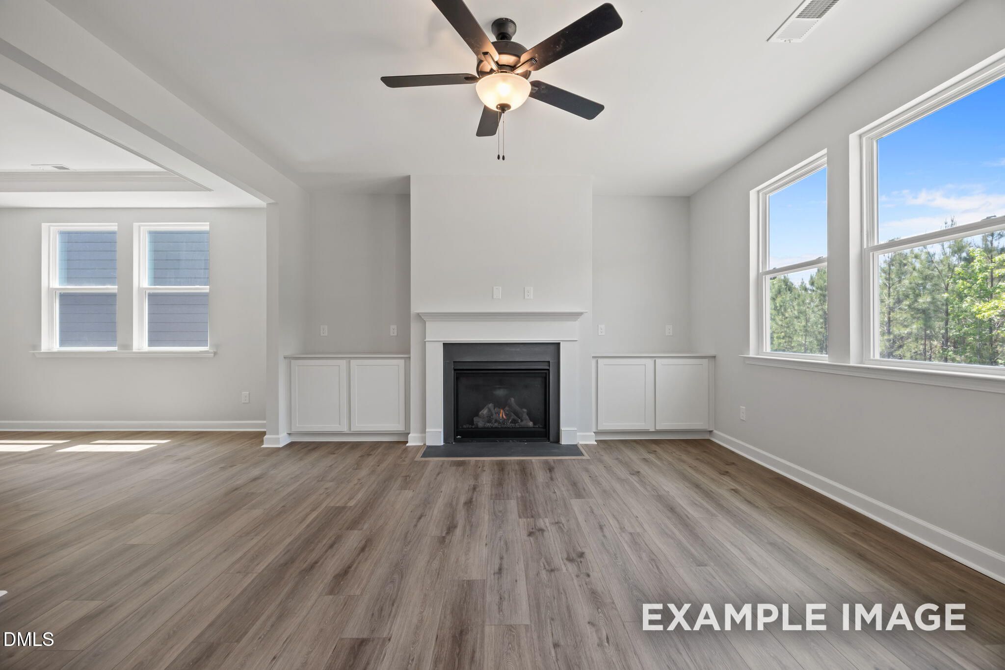 Bright living room with gas fireplace, built-in cabinets, ceiling fan, and hardwood floors in Davidson Homes The Beech, Wendell Ridge