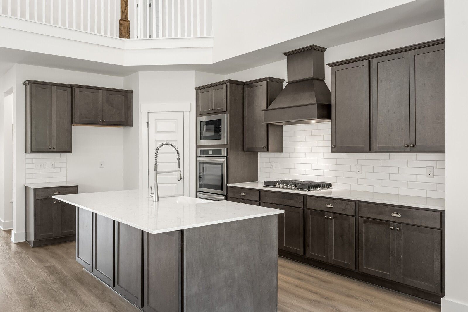 Modern kitchen with dark cabinets, quartz island, and stainless appliances in The Ridgeport C at Woods Crossing, Gallatin.