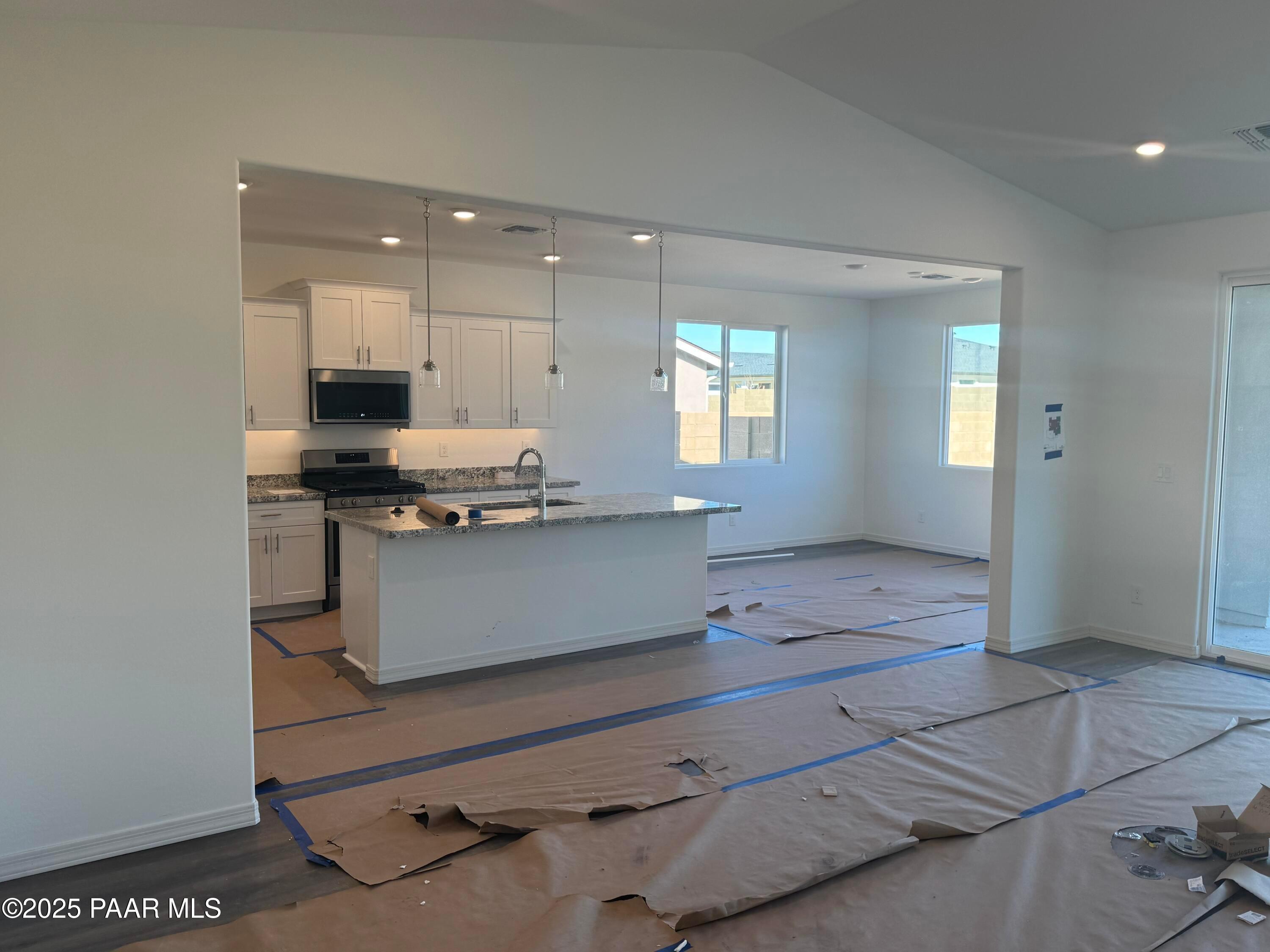 Modern open-concept kitchen with white cabinets, stainless appliances, and island overlooking living area in Davidson Homes The Summit A, Prescott Arizona