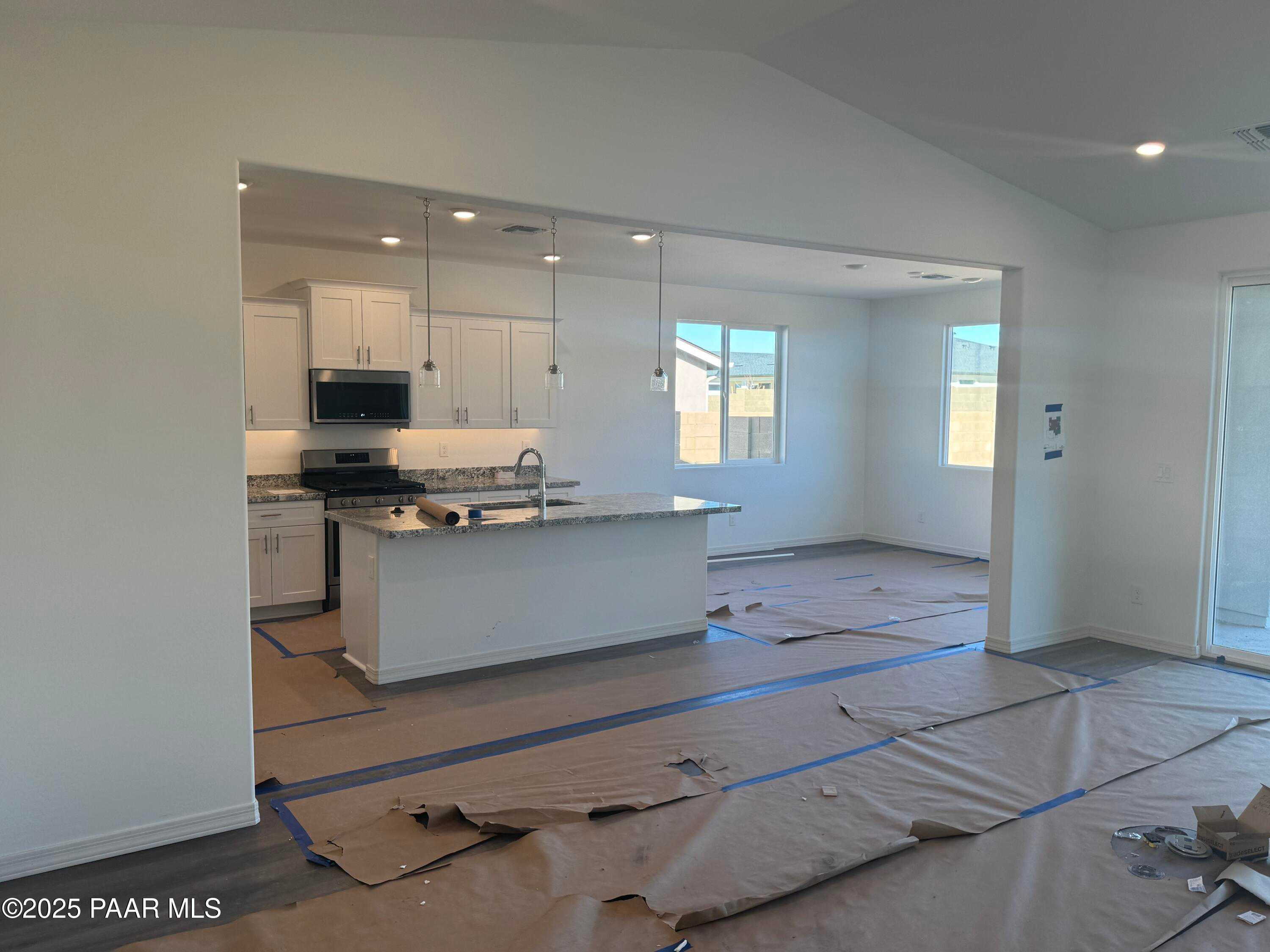 Modern open-concept kitchen with white cabinets, stainless appliances, and island overlooking living area in Davidson Homes The Summit A, Prescott Arizona