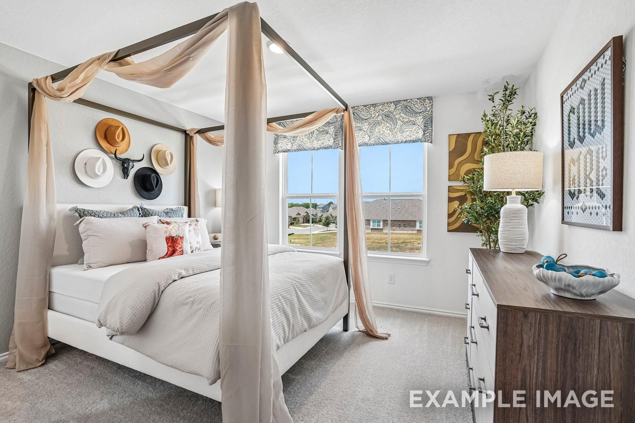 Elegant primary bedroom with canopy bed, western hat wall decor, and large windows in Davidson Homes Ashport J, Sundance Cove, Crosby TX