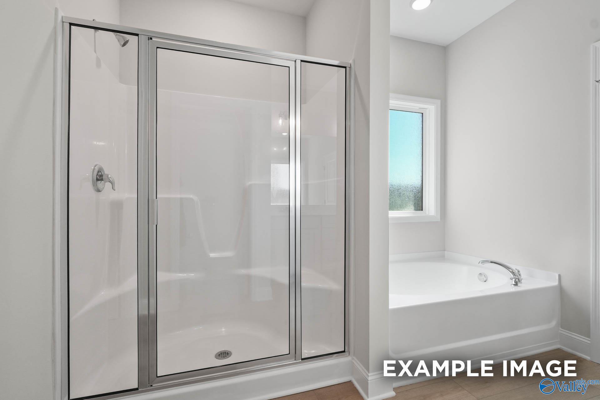 Modern master bathroom with glass-enclosed shower and soaking tub in The Everett B floor plan, The Meadows, Athens, AL.