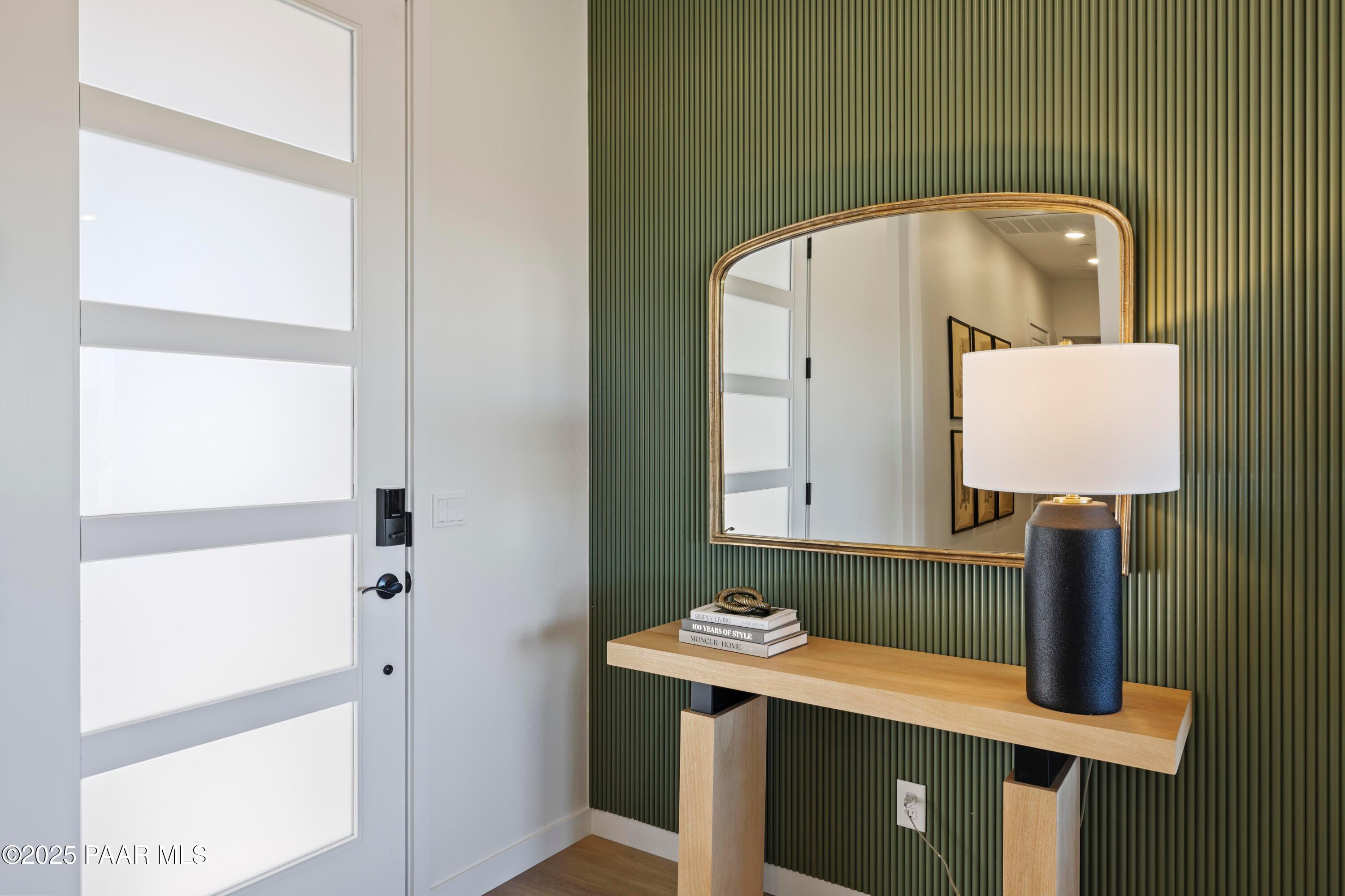 Elegant entryway featuring frosted glass door, green striped wall, gold mirror, and console table in Davidson Homes The Blaze D, Prescott, AZ