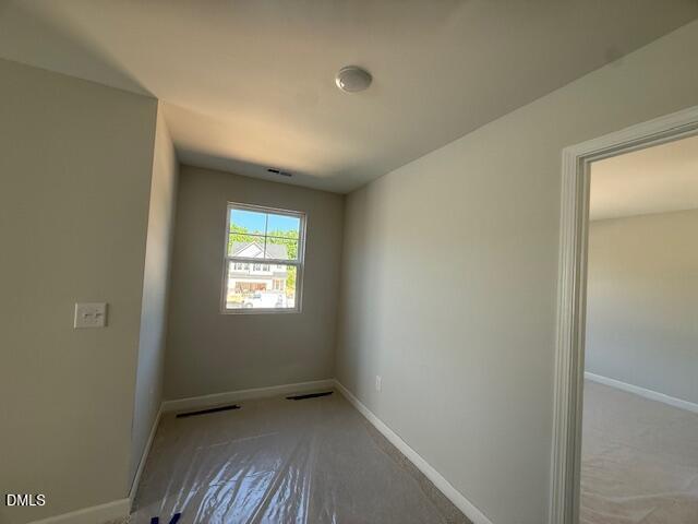 Bright secondary bedroom with neutral walls, large window, and protective flooring in Davidson Homes The Ash B, Zebulon NC