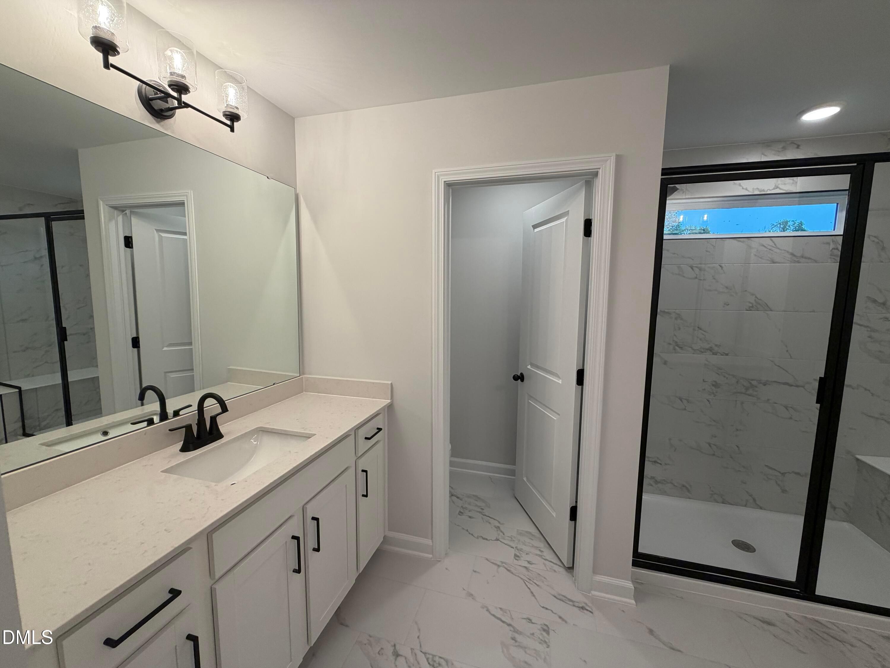 Modern bathroom with white vanity, black fixtures, and glass walk-in shower in Davidson Homes The Preston C, Wendell Ridge, NC