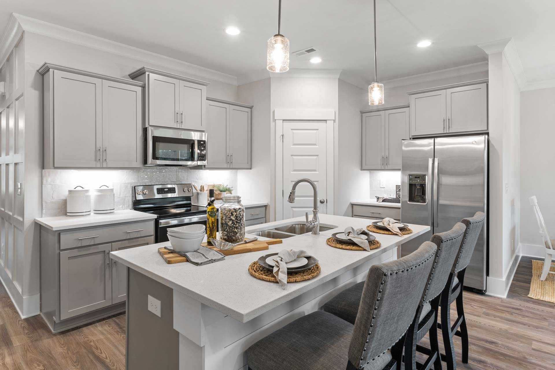 Spacious modern kitchen in The Meadows Athens Alabama with gray shaker cabinets white quartz island stainless steel appliances and pendant lights
