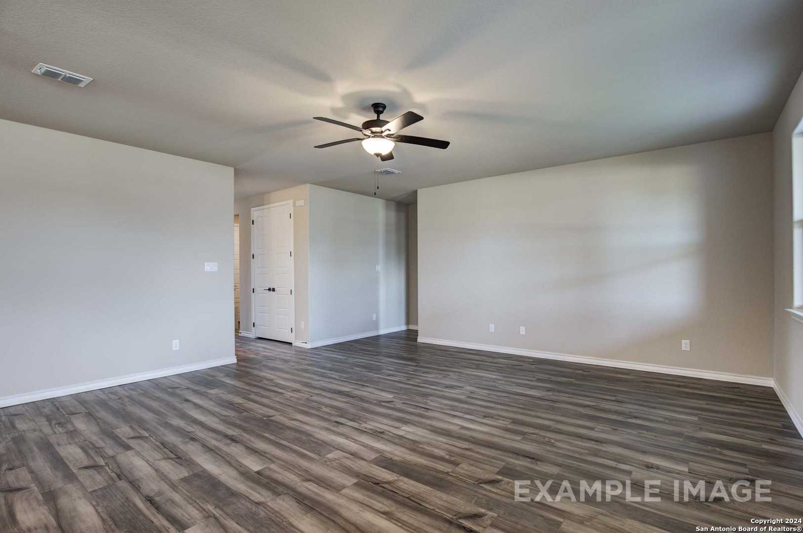 Spacious hallway with ceiling fan, neutral walls, and hardwood floors in Davidson Homes The Rockford G, Ladera, San Antonio