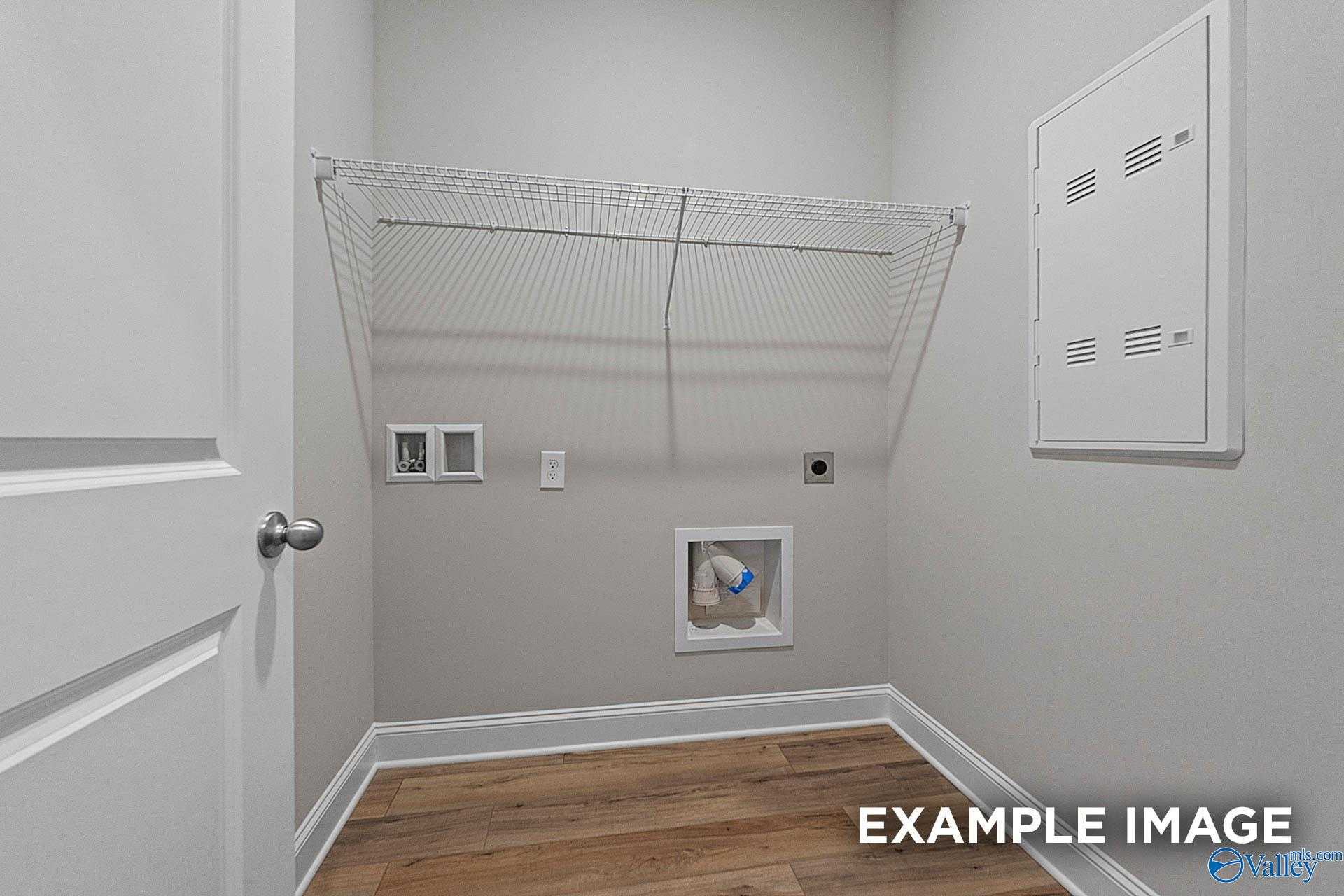 Functional laundry room with wire shelving, washer-dryer hookups, and hardwood floors in Davidson Homes The Franklin E, Hazel Green, Alabama