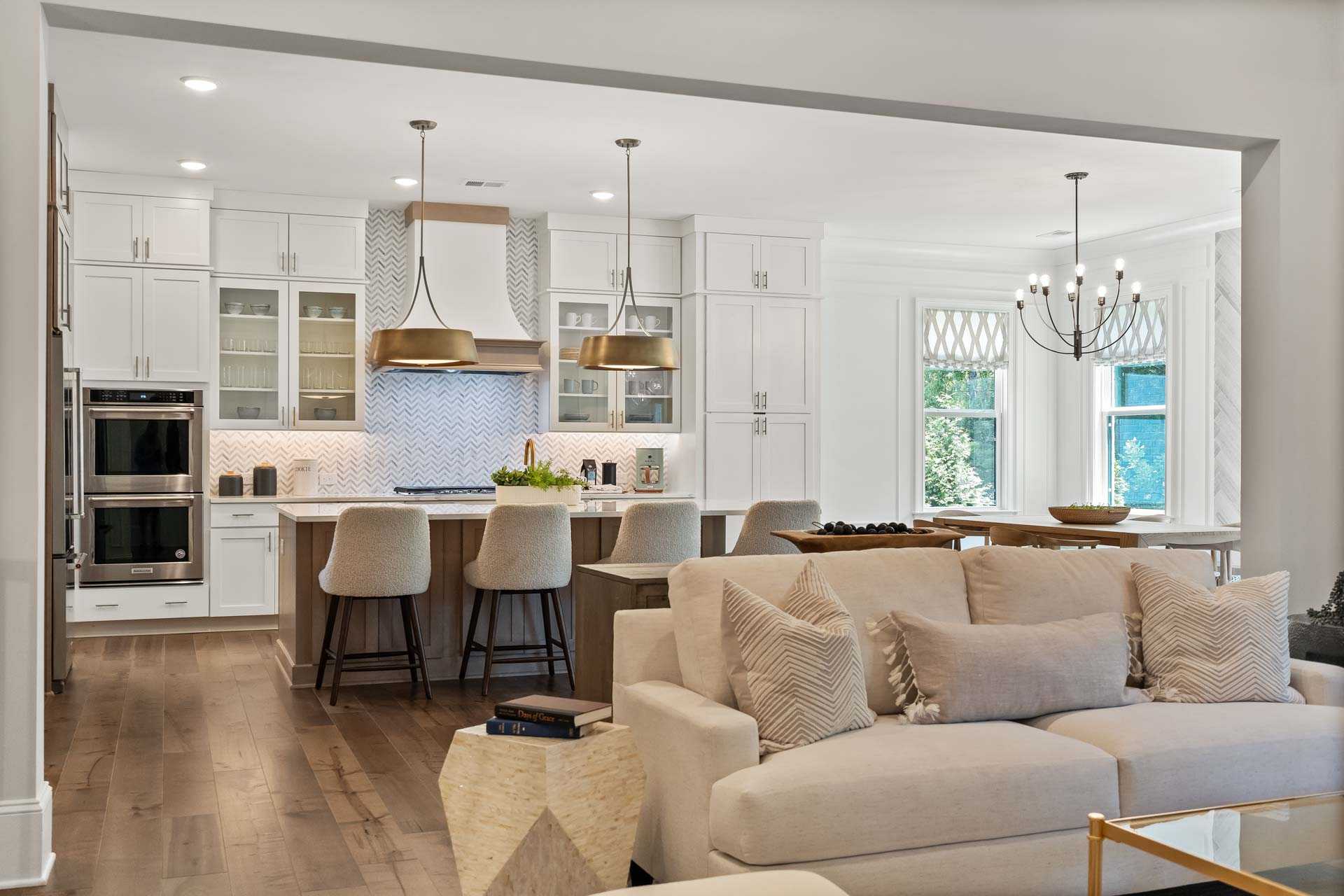 Open-concept kitchen living room in Tanglewood East Cobb GA with white cabinets, island seating, hardwood floors, beige sofa