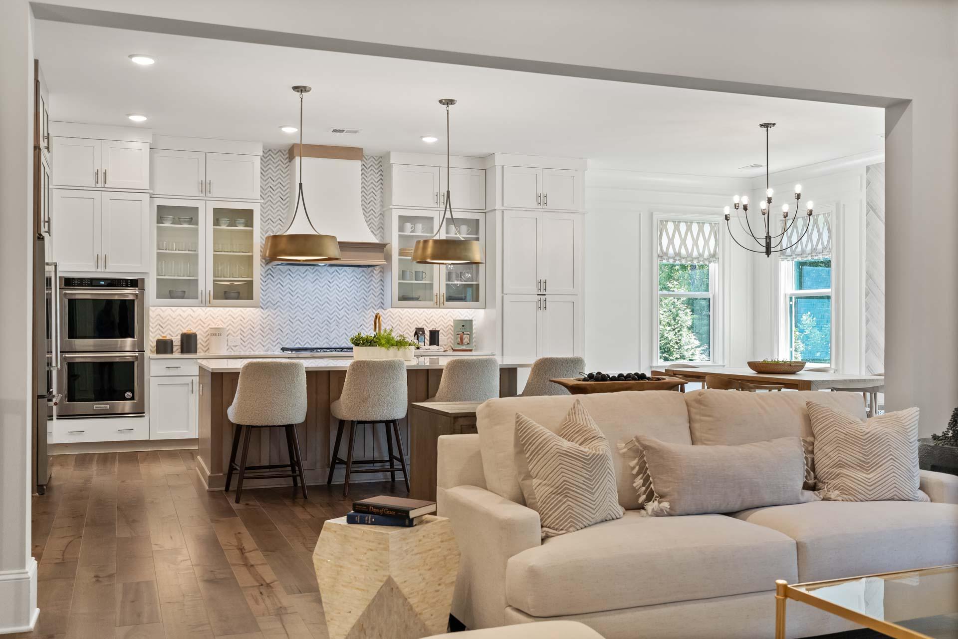 Open-concept kitchen living room in Tanglewood East Cobb GA with white cabinets, island seating, hardwood floors, beige sofa