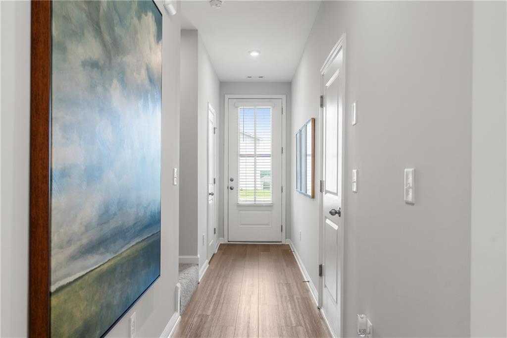Elegant hallway with light gray walls, hardwood floors, abstract blue painting, and glass French doors in Davidson Homes The Durant A, Emerson, GA