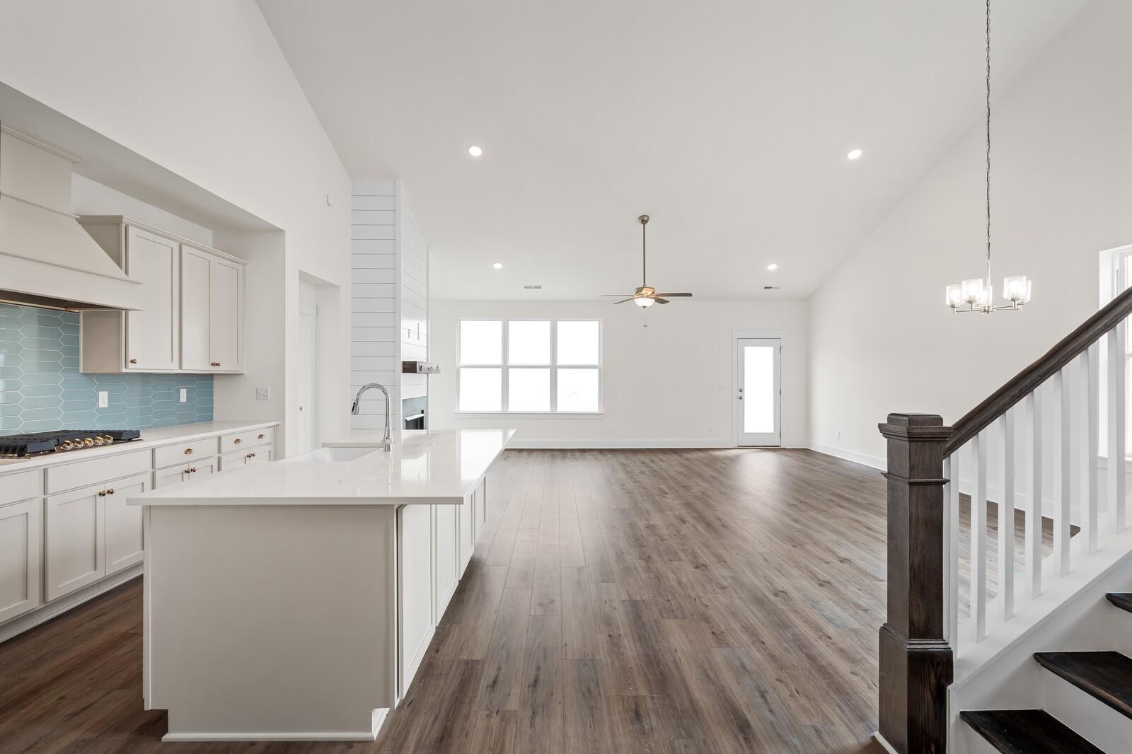 Open-concept kitchen with white cabinets, blue backsplash, and island in The Ridgeport home by Davidson Homes, Gallatin, TN