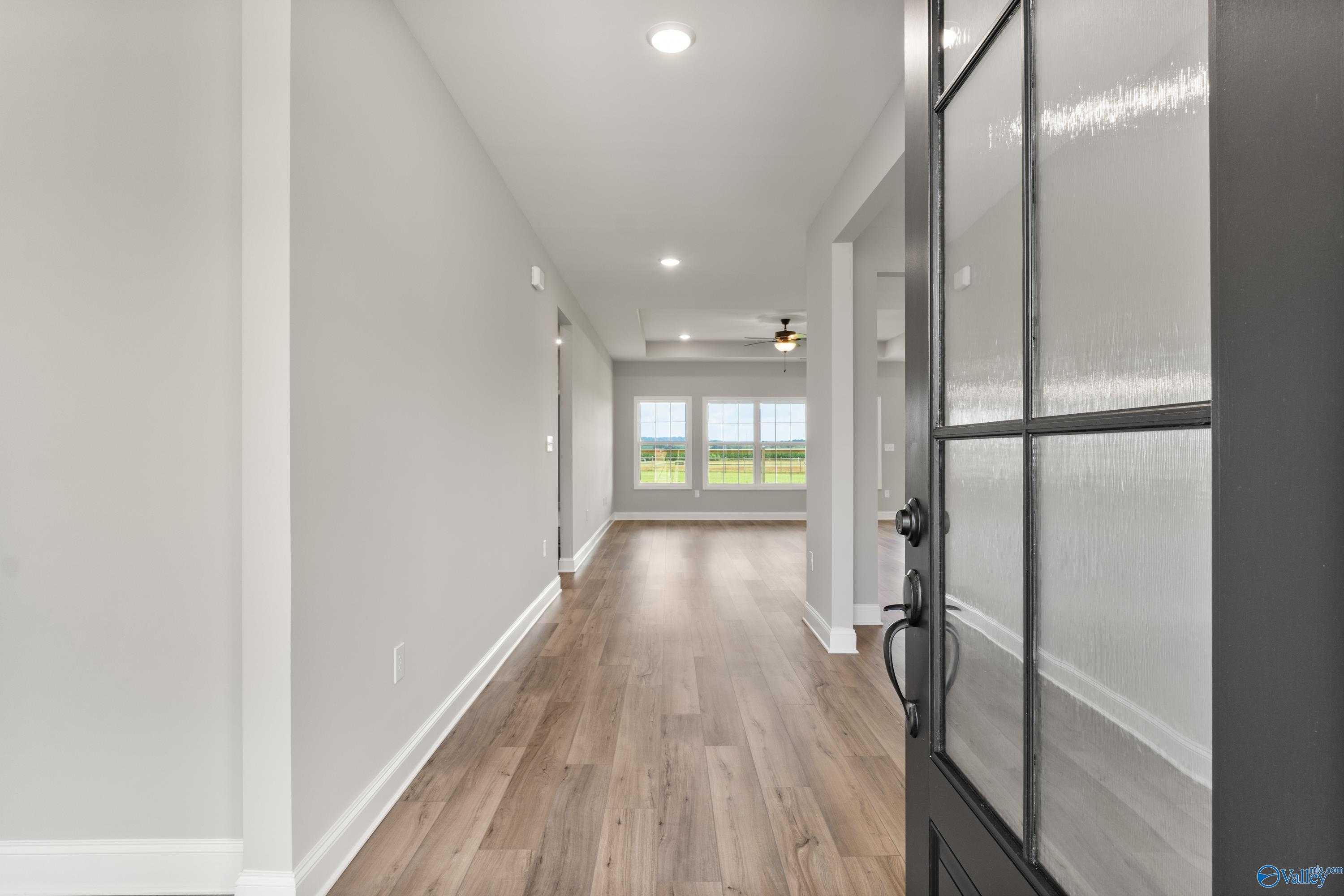 Bright hallway with light gray walls, hardwood floors, and frosted glass back door in The Finleigh by Davidson Homes, Toney, AL