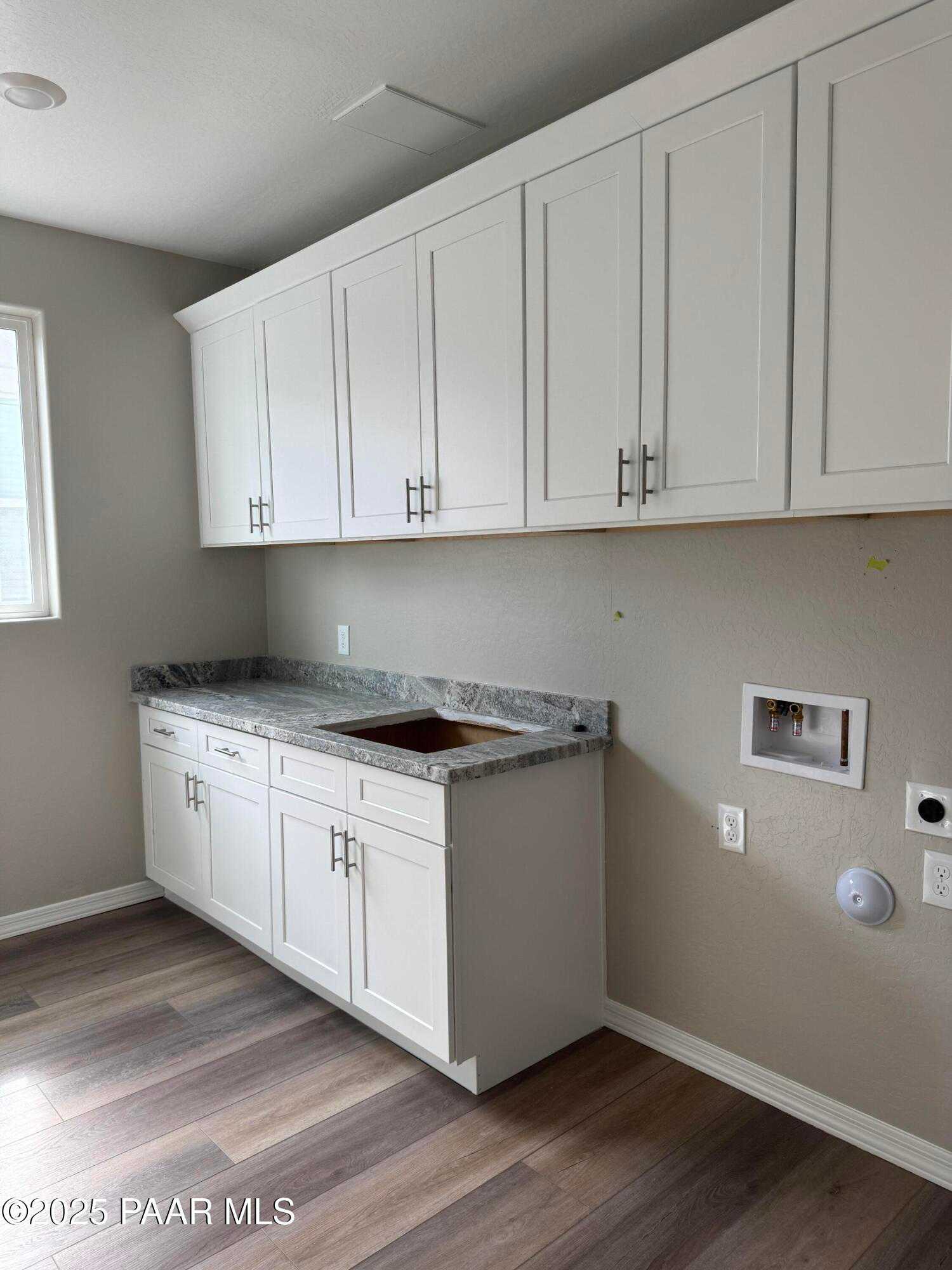Modern laundry room with white shaker cabinets, granite countertop, utility sink in Davidson Homes The Monarch A, Prescott, Arizona