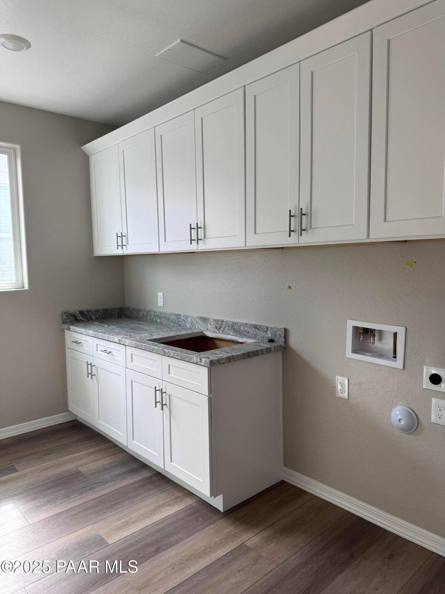 Modern laundry room with white shaker cabinets, granite countertop, utility sink in Davidson Homes The Monarch A, Prescott, Arizona
