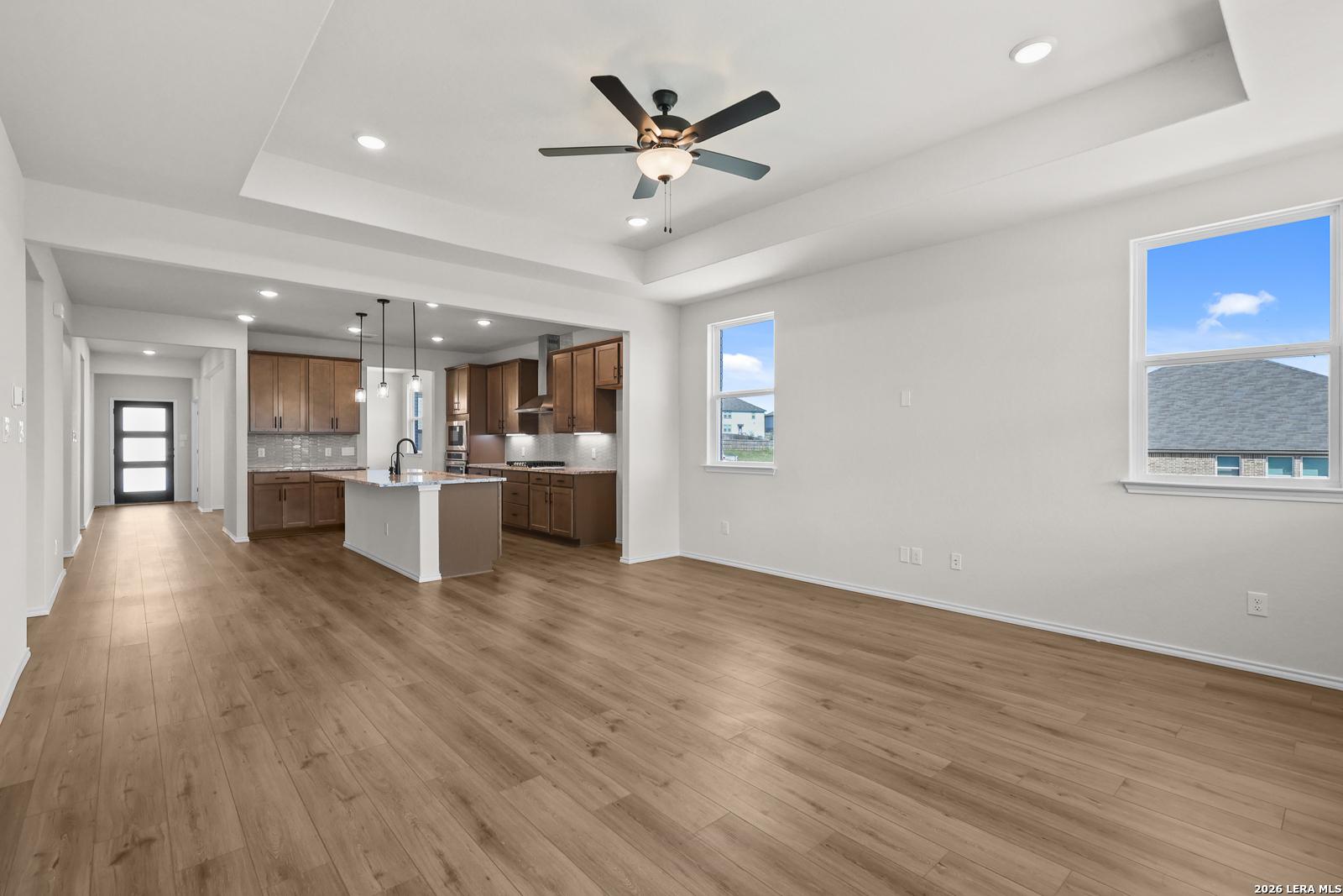 Open-concept living area with wood-look flooring, tray ceiling, and kitchen island in Davidson Homes Glenwood E, San Antonio TX