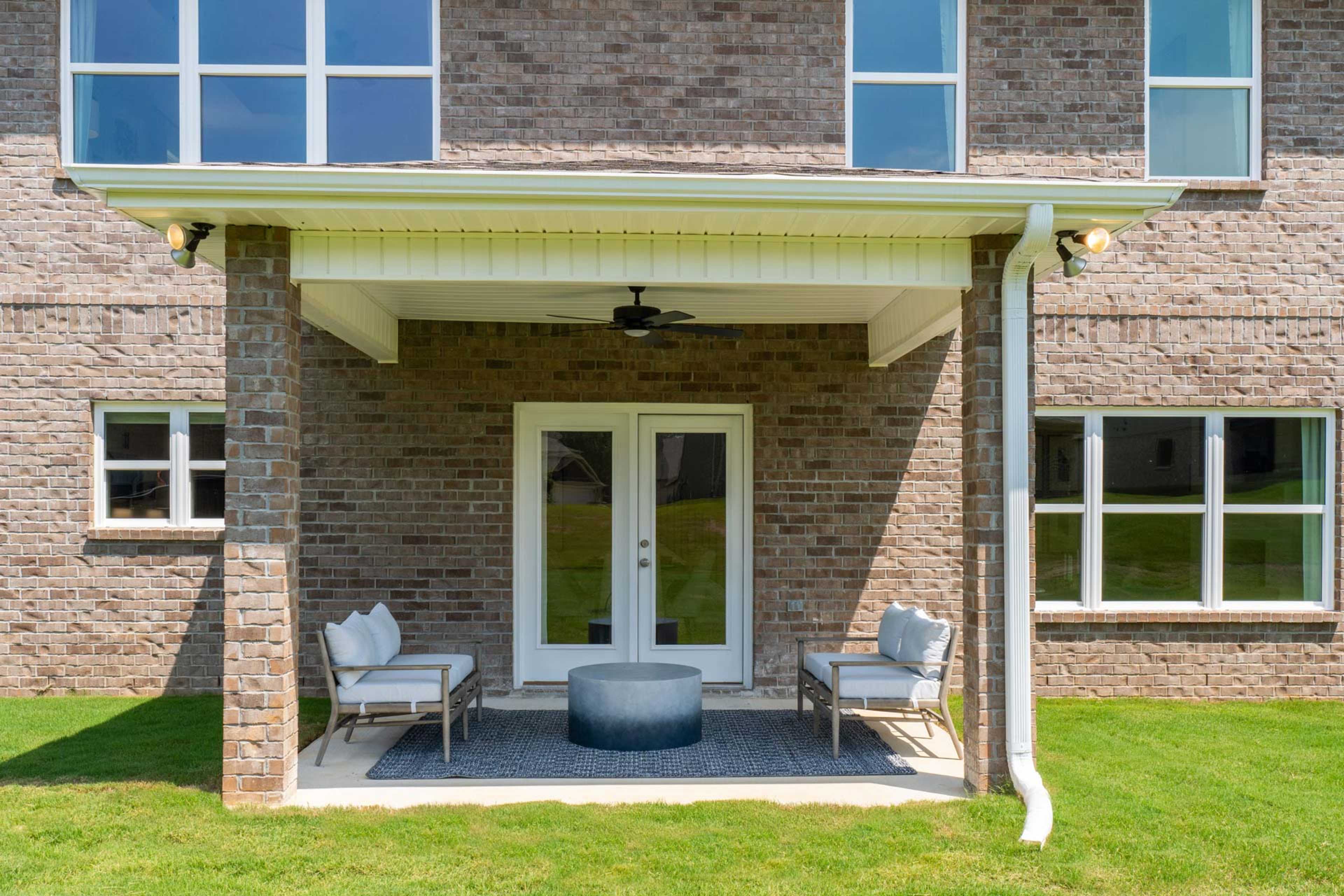 Covered back patio at Creek Grove in New Market Alabama with brick exterior, French doors, ceiling fan, and lounge seating