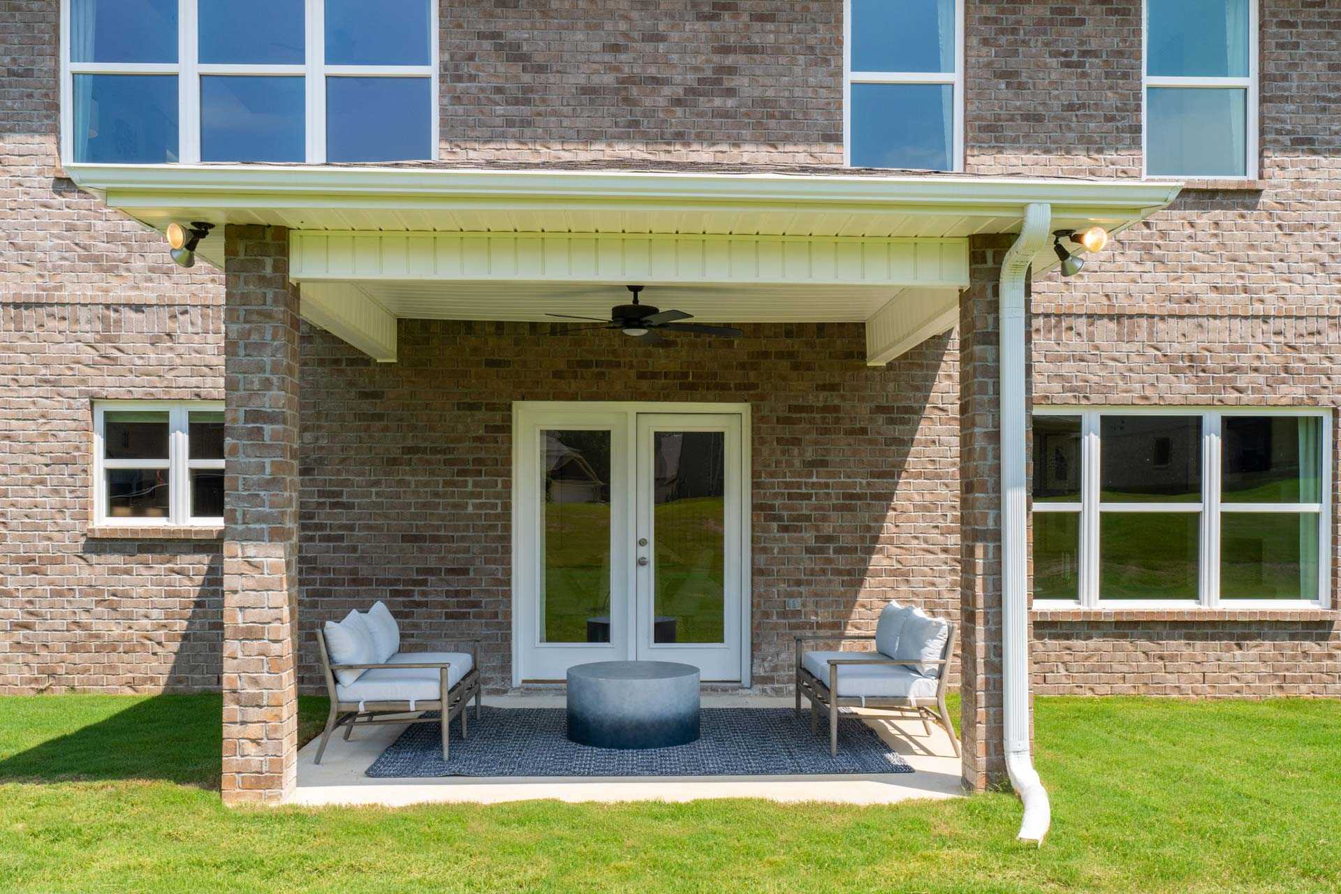 Covered back patio at Creek Grove in New Market Alabama with brick exterior, French doors, ceiling fan, and lounge seating